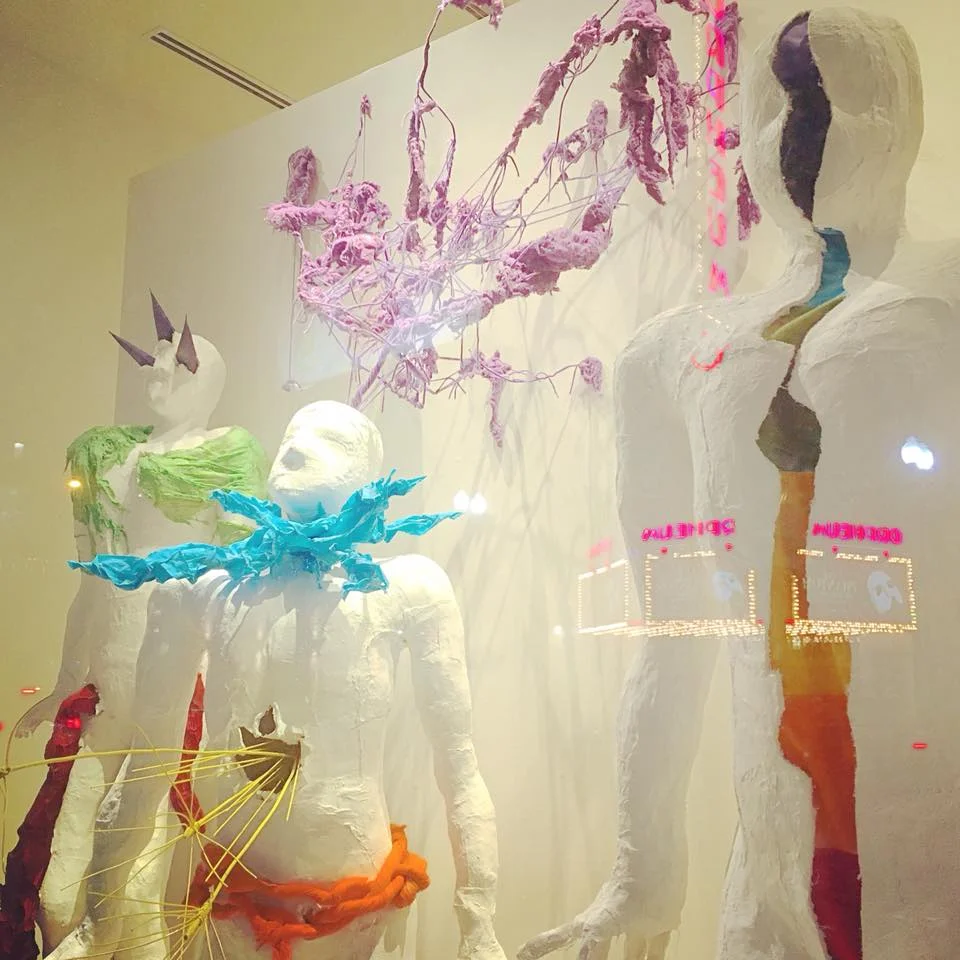 detail of figures, installed, with reflection of theatre from across the street