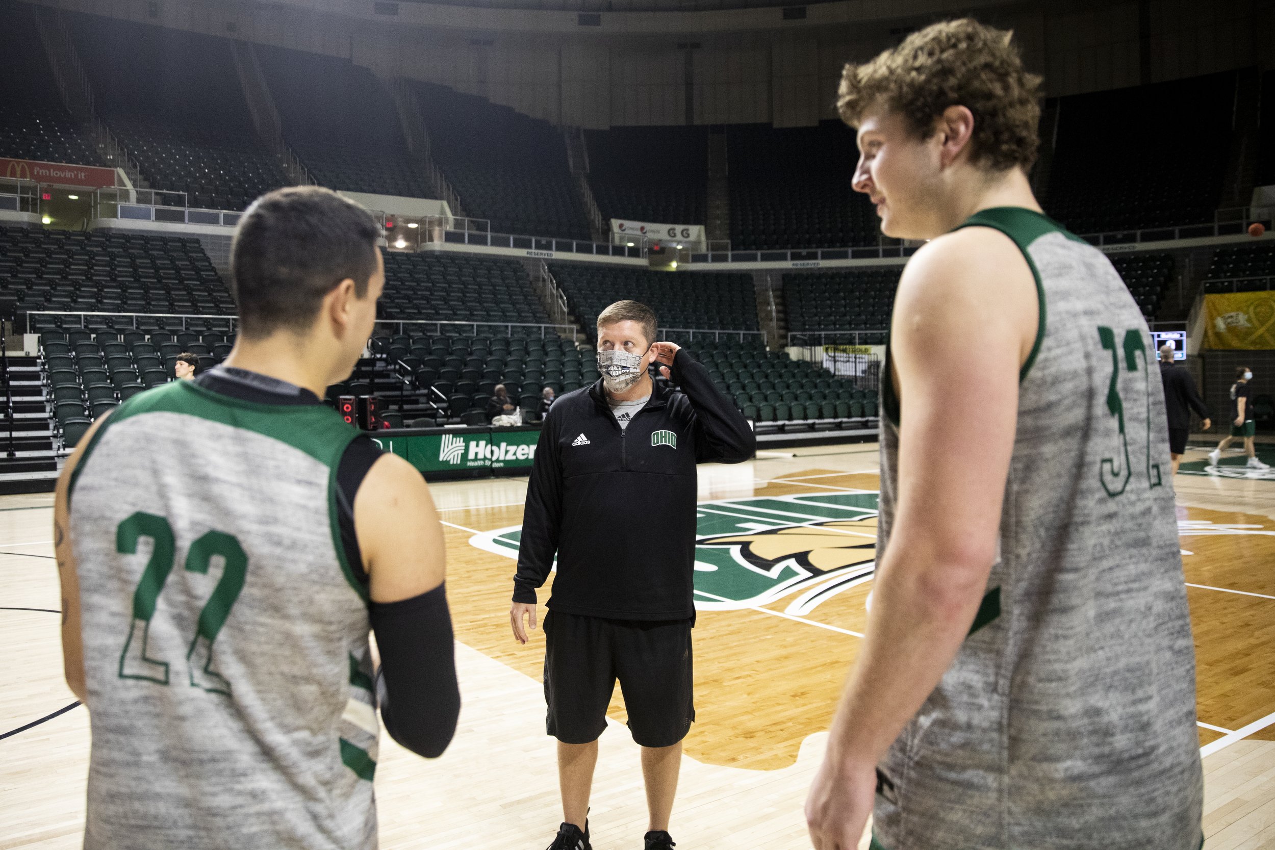  Ohio assistant coach, Kyle Barlow, talks with Tommy Schmock (22, left) and Colin Granger (32, right) about fantasy football in the shoot-around prior to practice. The guys stay socially distanced when it’s in an attempt to keep the players safe.  