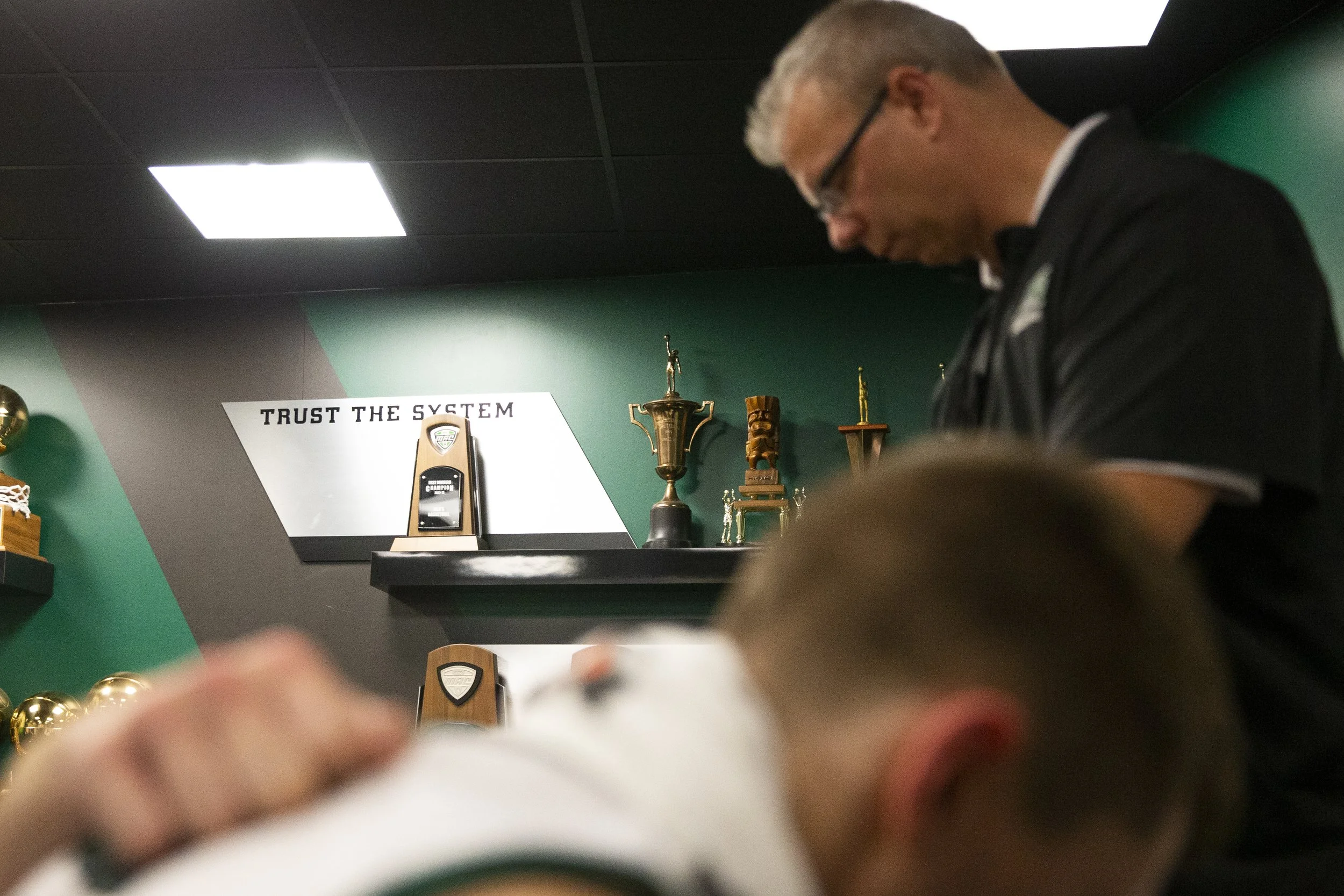  The team kneels for a post-game prayer after the debrief. The quote “trust the system” was installed when Boals arrived and tells the players that if they trust in the system that is put in place, great things will happen.  