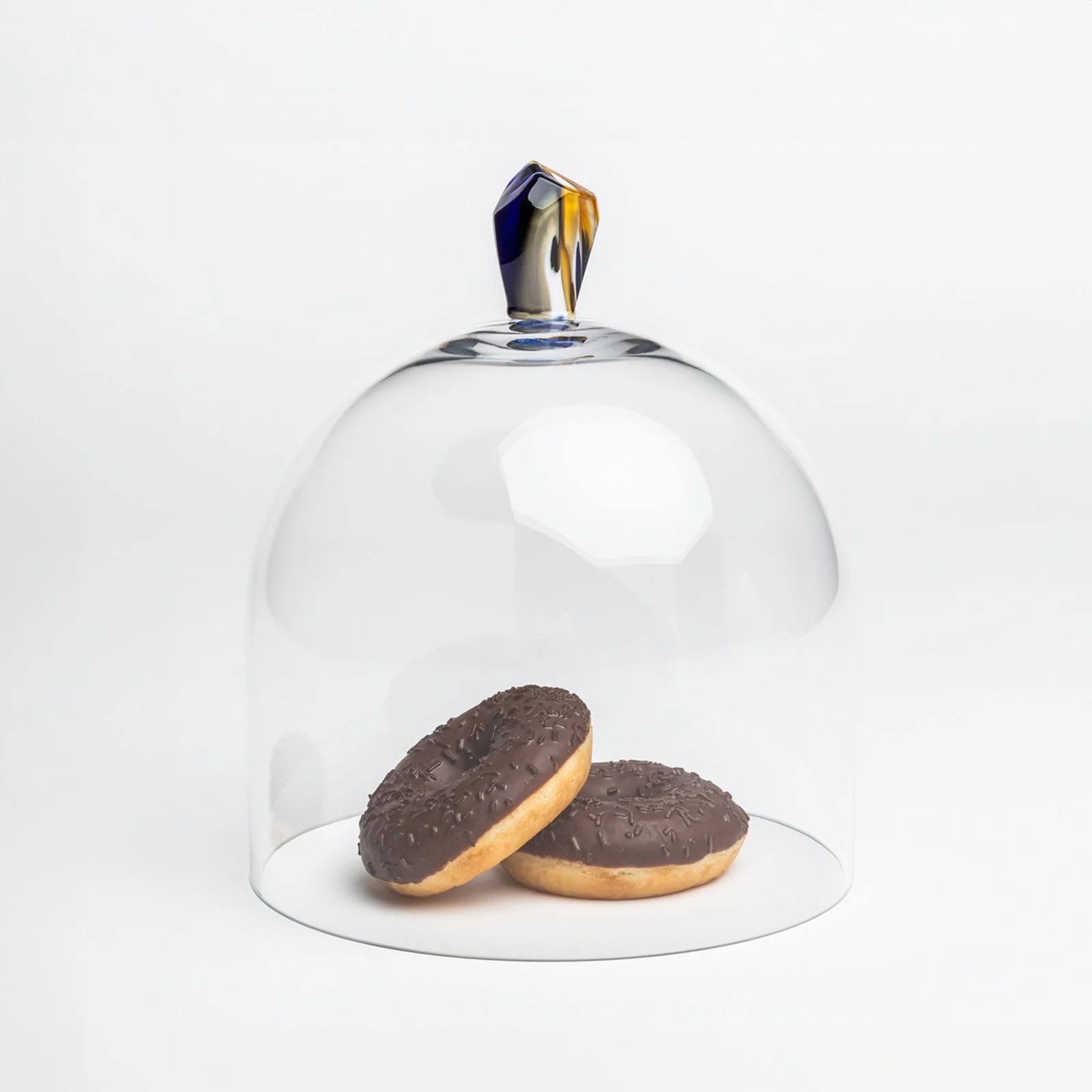 Elegant glass dome with colorful handle, placed over donuts for display and serving.