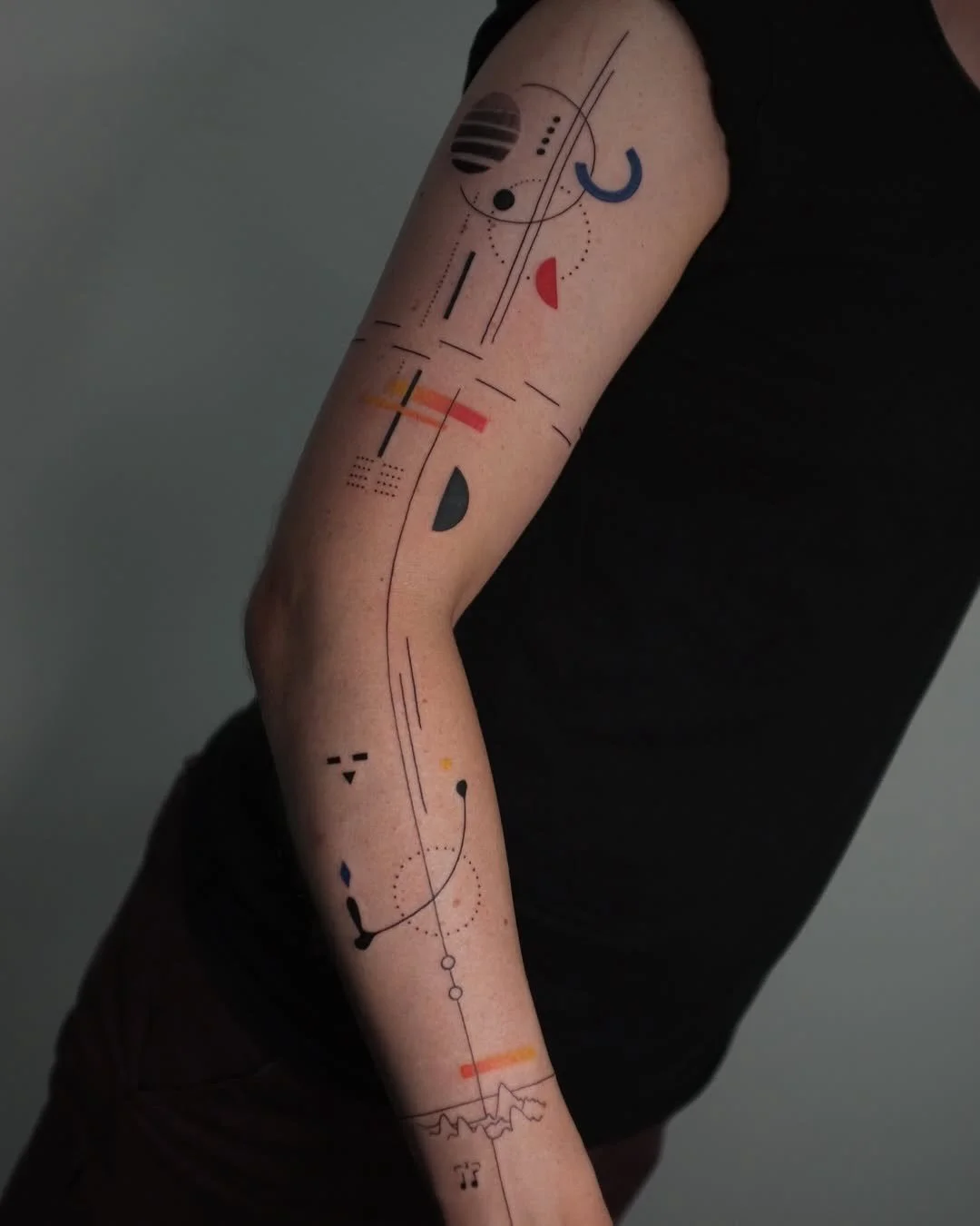 @kirii.lines abstract fine line 

Inspired by abstract art and Bauhaus design, Kirii composes each piece like a painting on the body. One long line guides the flow, bold shapes balance with empty skin, and small pops of blue, red and yellow lead the 