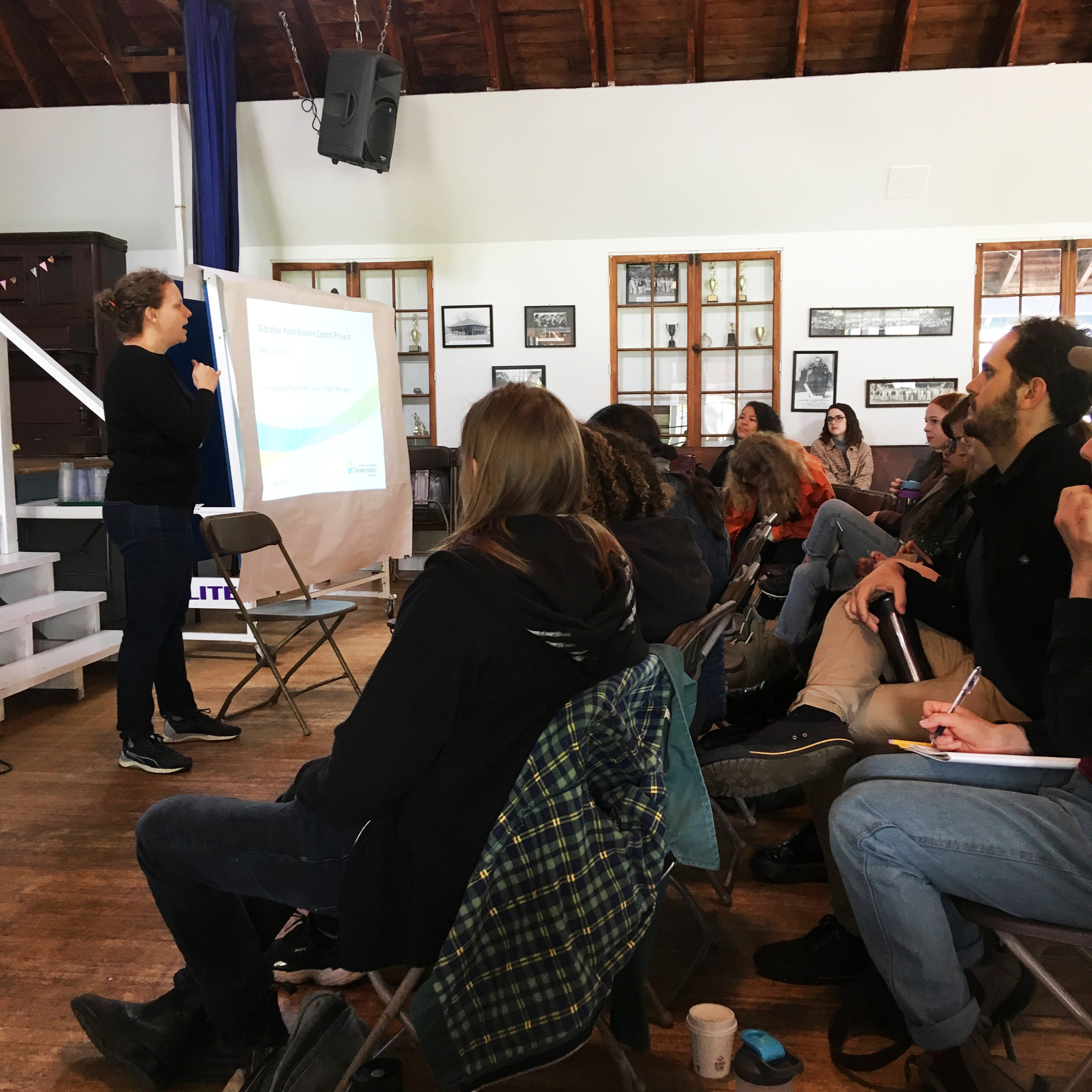 Meg St. John presents work undertaken by the Toronto Regional Conservation Authority to protect Toronto Islands while outside news crews gather to cover a possible evacuation