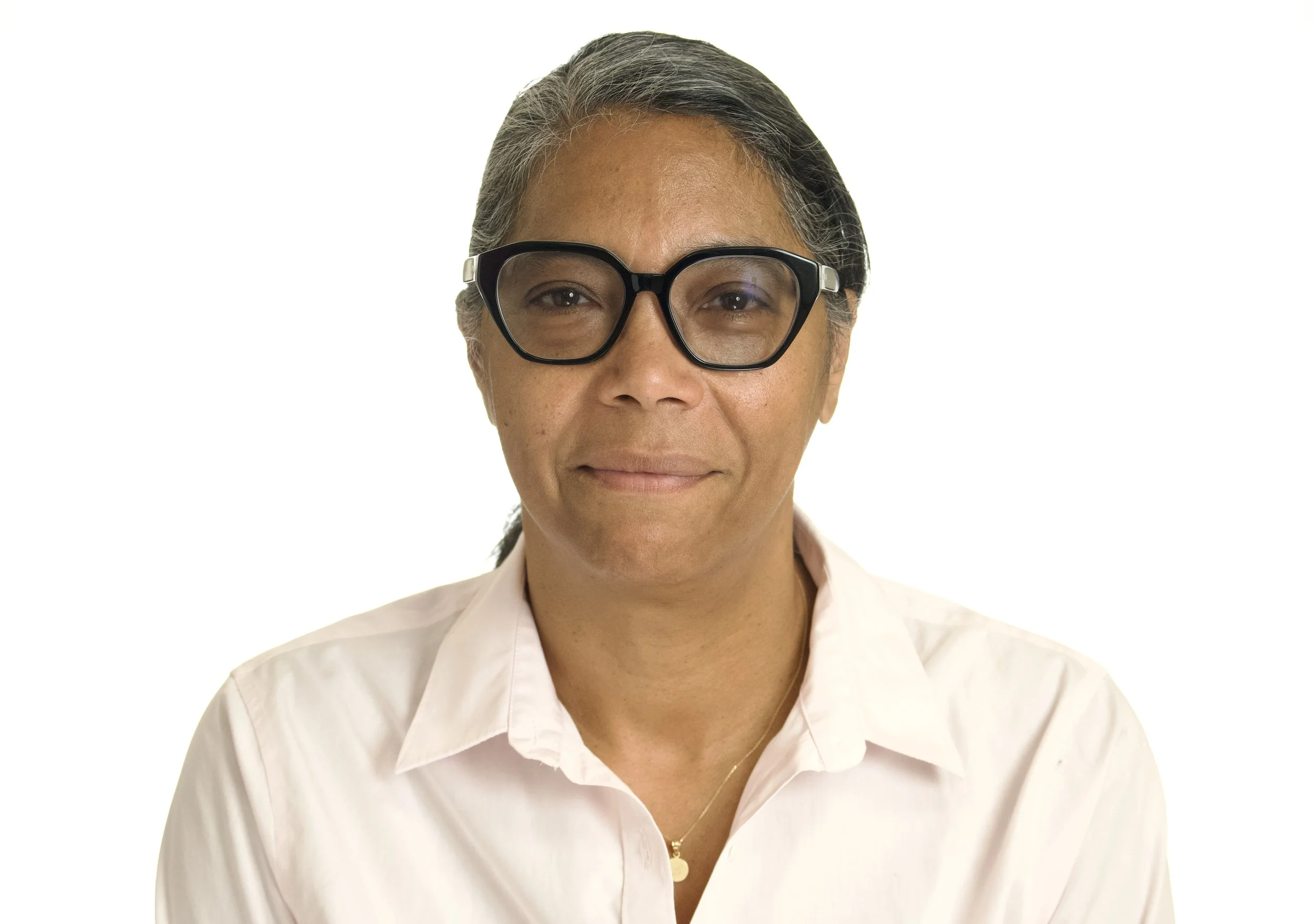 A middle-aged woman with glasses and gray hair, wearing a light pink shirt against a white background.