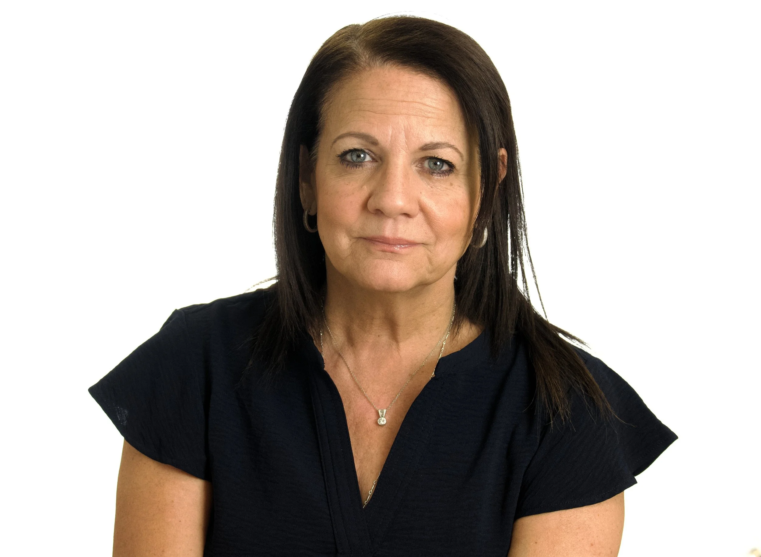 Portrait of a middle-aged woman with dark brown hair, wearing a black top and jewelry, against a white background.
