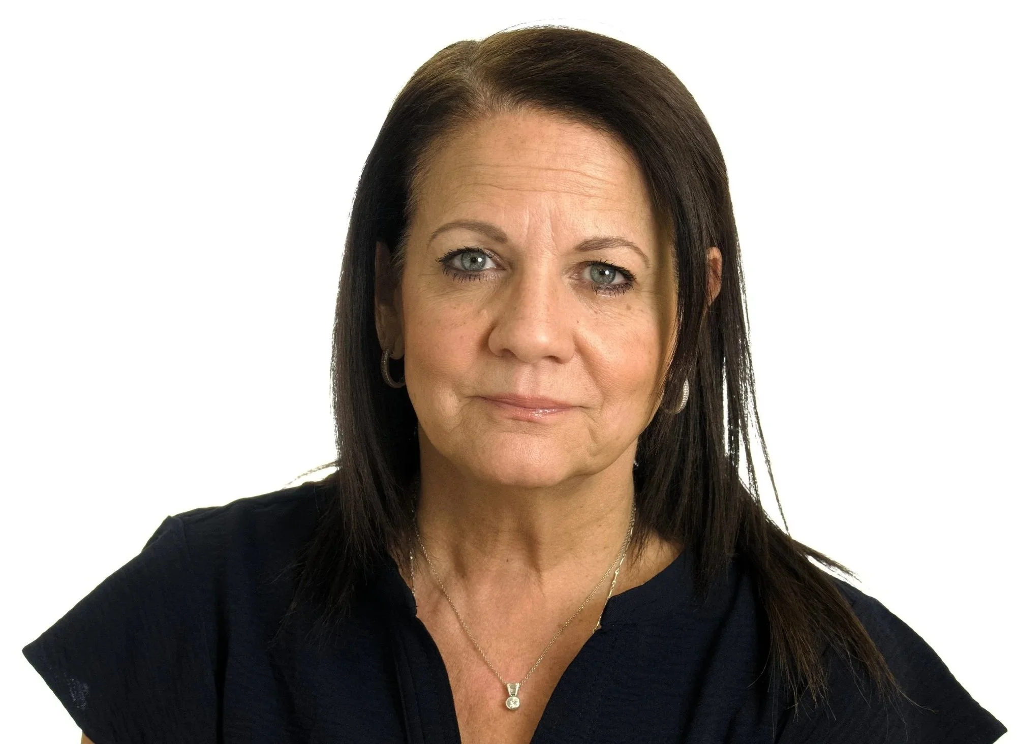 Portrait of a middle-aged woman with dark brown hair, wearing a black top and jewelry, against a white background.