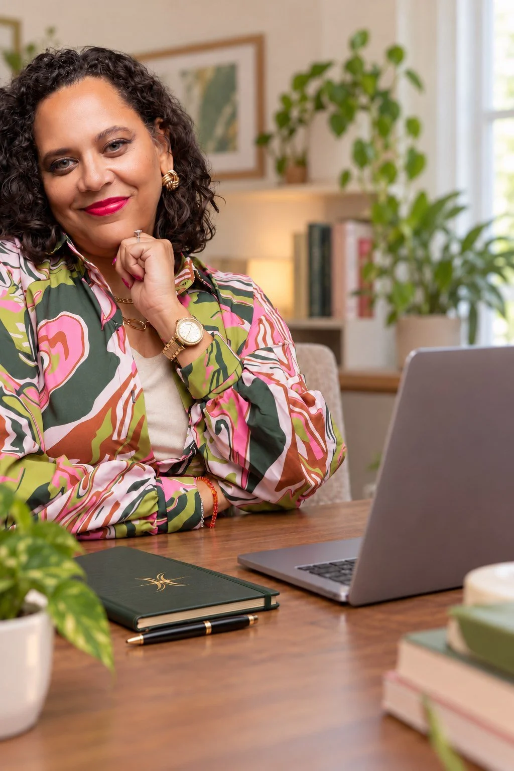 Denise Ransom at her desk with a laptop and a green Sacred Middle journal