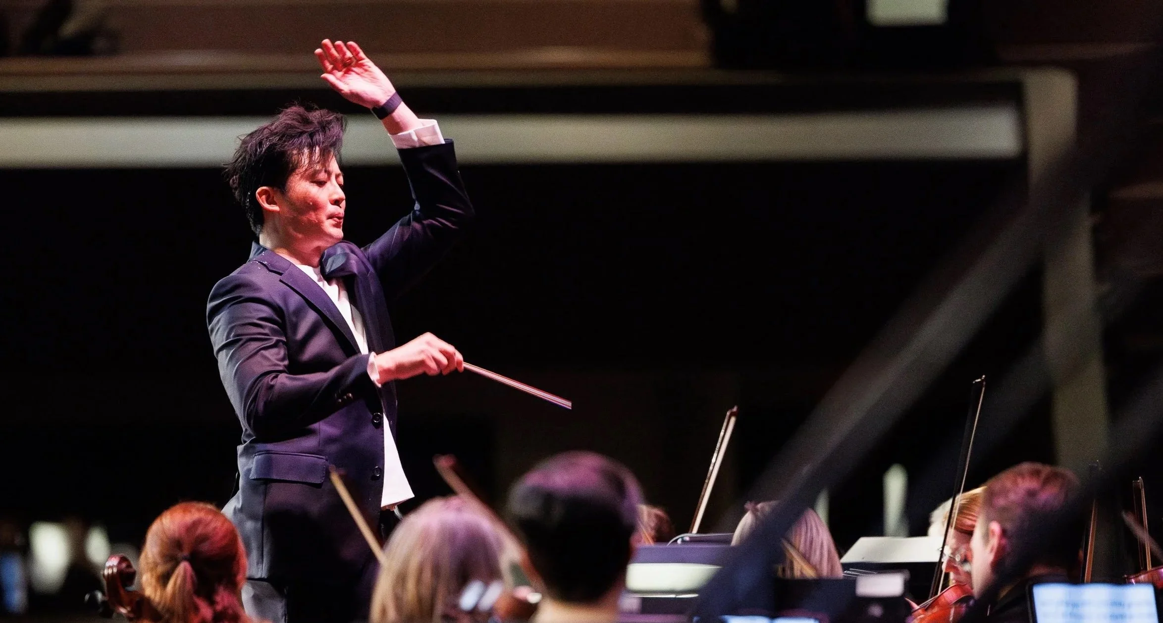 Henry Cheng conducts an orchestra in performance.
