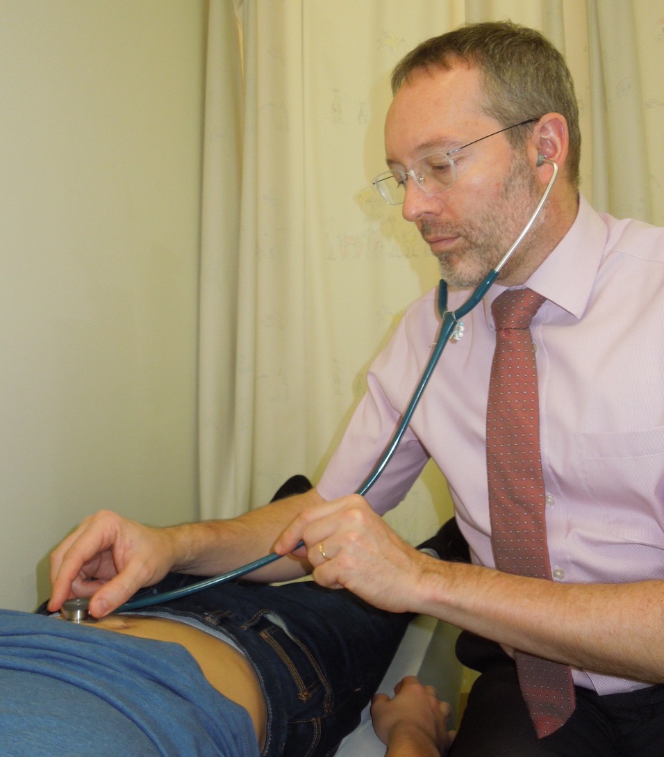 Dr Marcus Auth performing auscultation of abdomen in paediatric gastroenterology examination. 