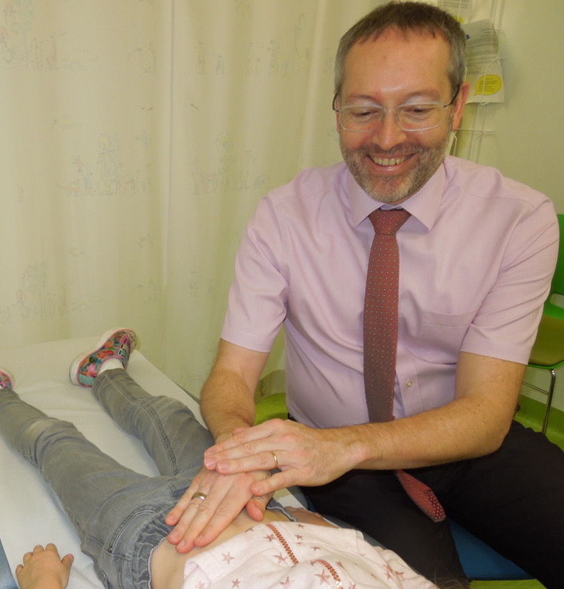 Dr Marcus Auth palpating abdomen as part of paediatric gastroenterology examination. 