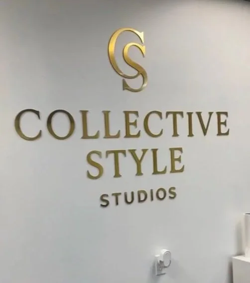 Logo of Collective Style Studios on a wall with gold lettering and emblem.