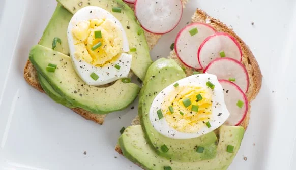 Sliced avocado, hard-boiled egg, and radish on toast