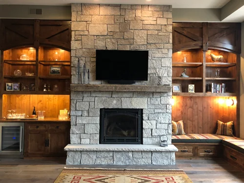 Accent lighting highlights the left side bar cabinet and the right side cozy reading nook. The space is topped off with personal accessories and enough seat cushions to accommodate a crowd.