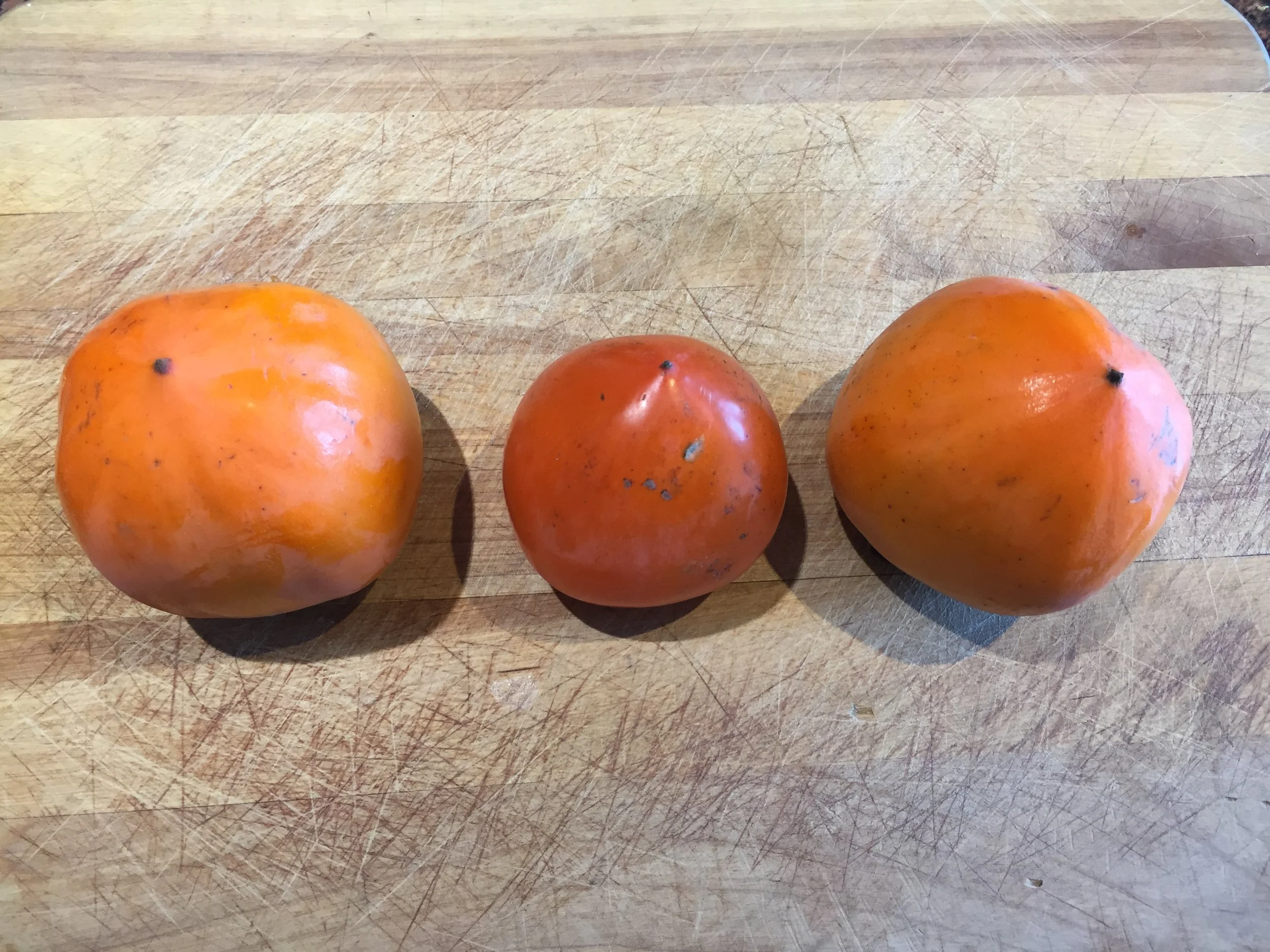 Hachiya Persimmons - the two on either end are still hard but the middle one is soft and ripe, note the translucent and deeper colored skin.