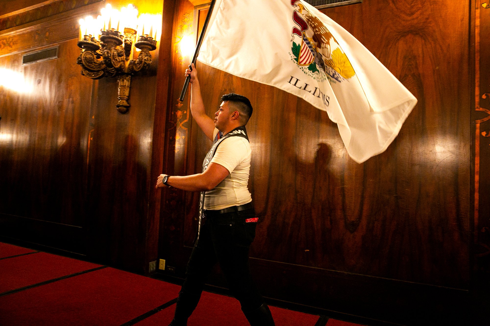  Butch Romero, Mr. Chicago 2020, walks on stage with the Chicago flag during the Opening Ceremonies of International Mister Leather 45, held in The Florentine Room at The Congress Plaza Hotel, Thursday May 25, 2023, Chicago, IL.  