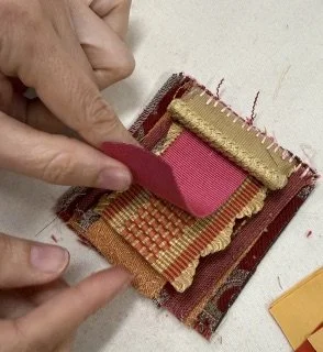 Hand lifting page of small fabric book made with red and beige trim pieces