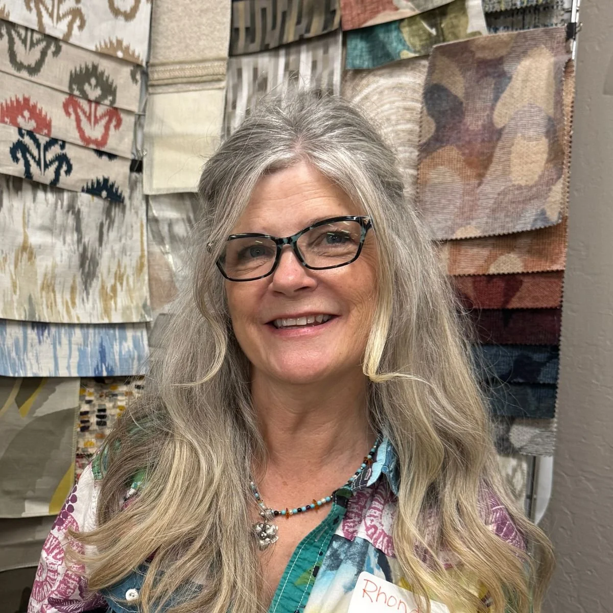 Smiling woman with long silver hair and black rimmed glasses