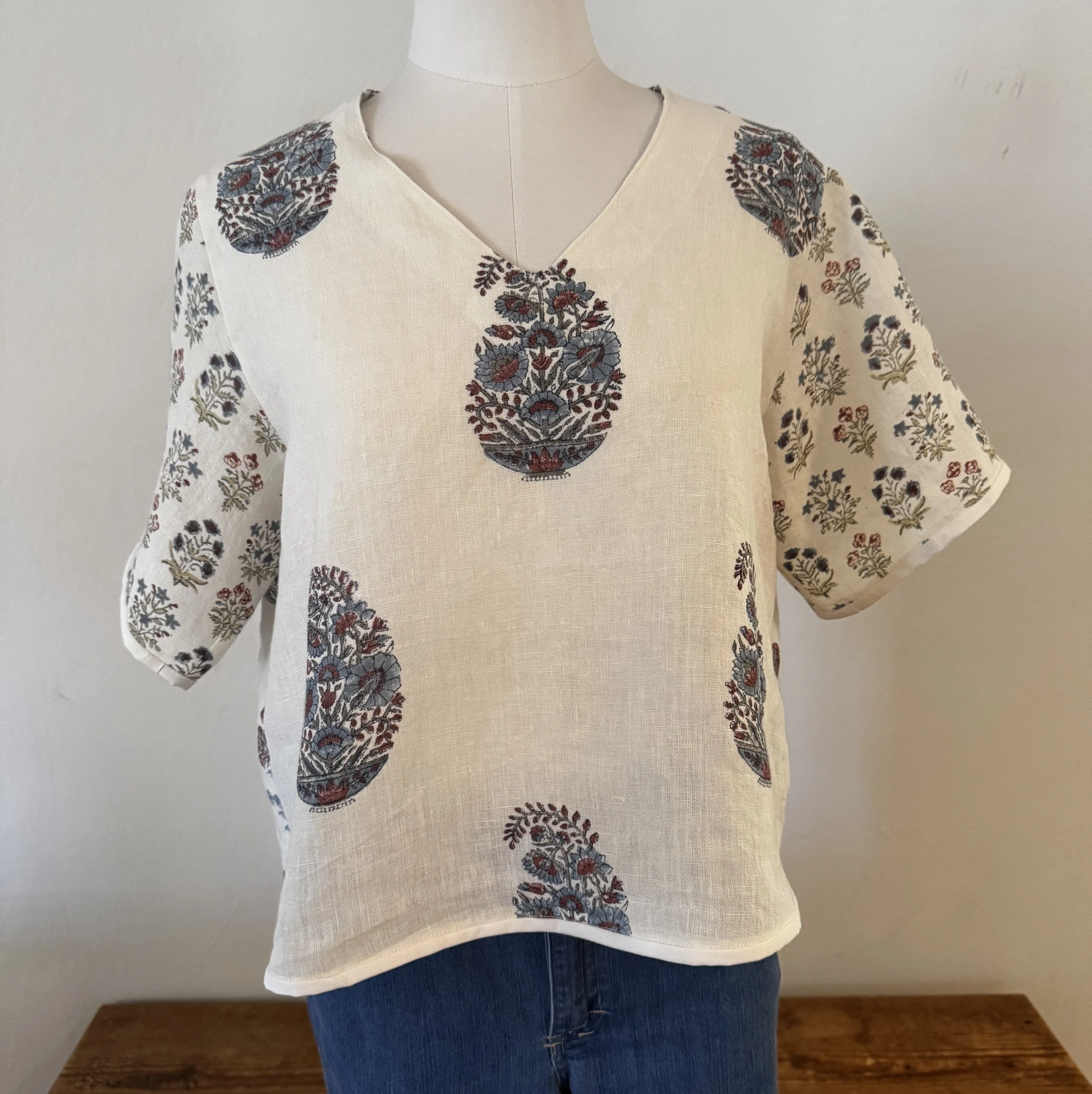 Mannequin modeling off-white blouse with floral designs