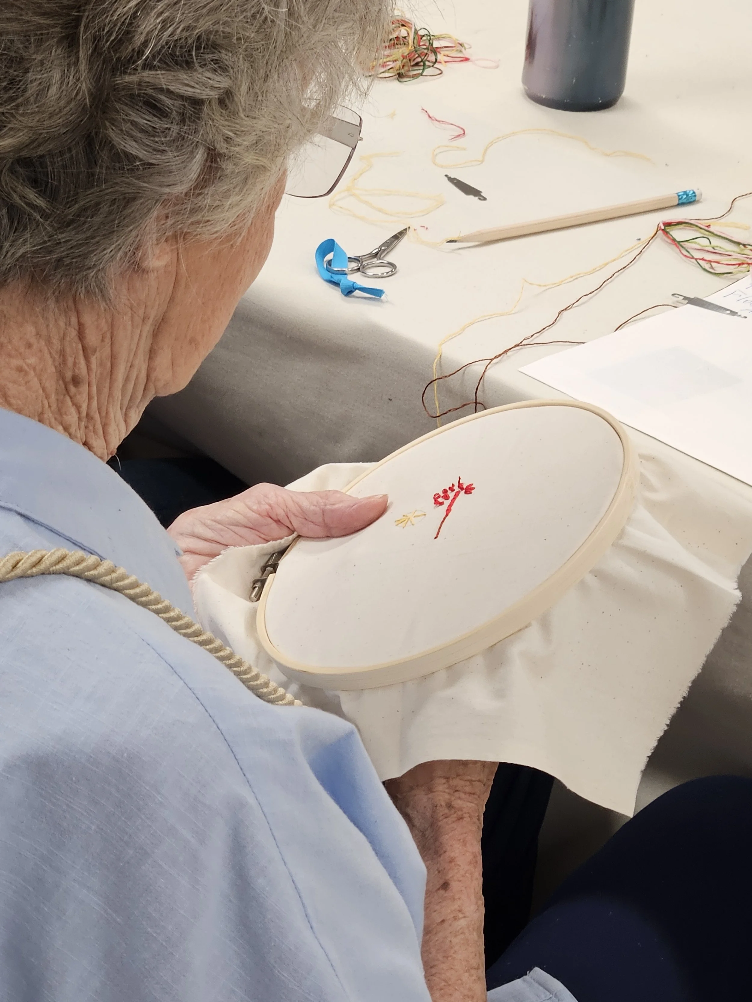 Close-up of woman holding embroidery hoop with red embroidery
