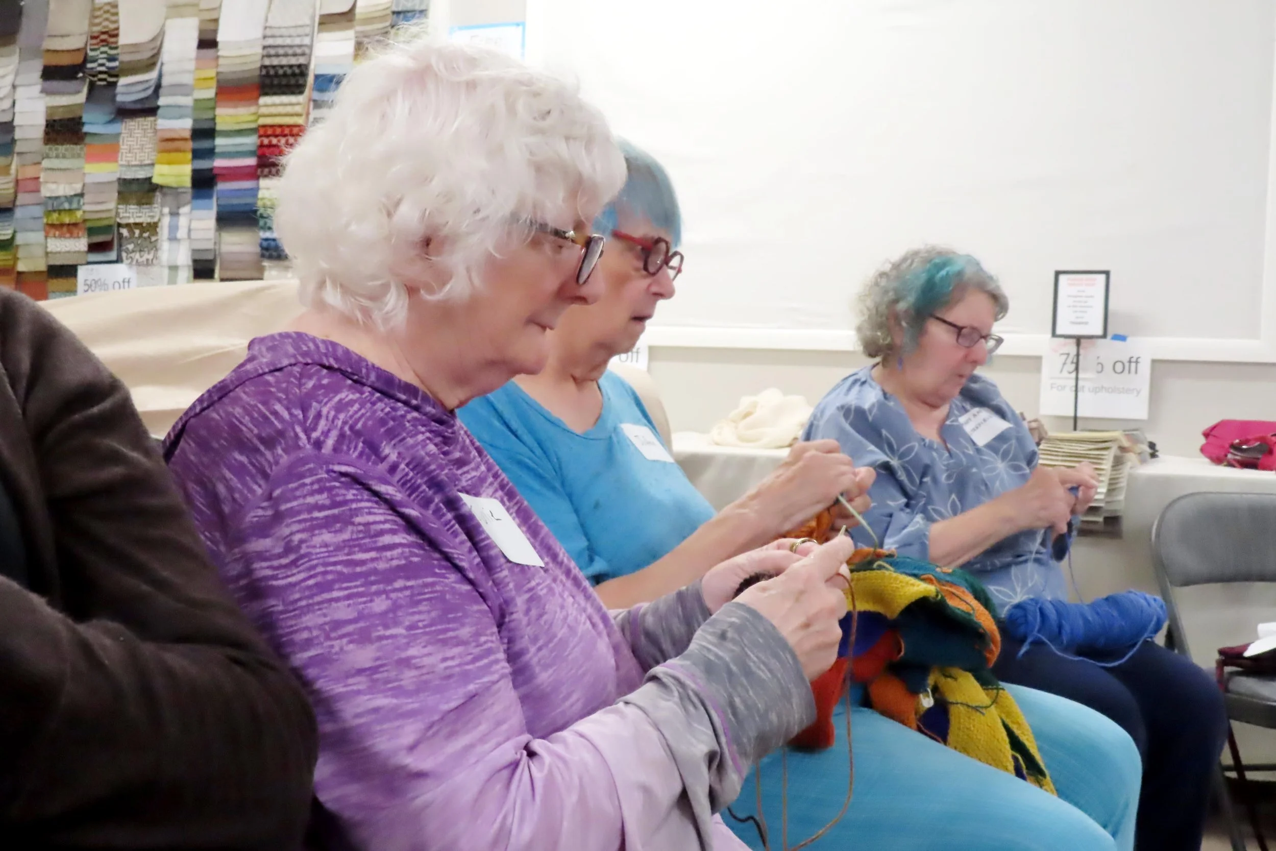 Three seated women knitting