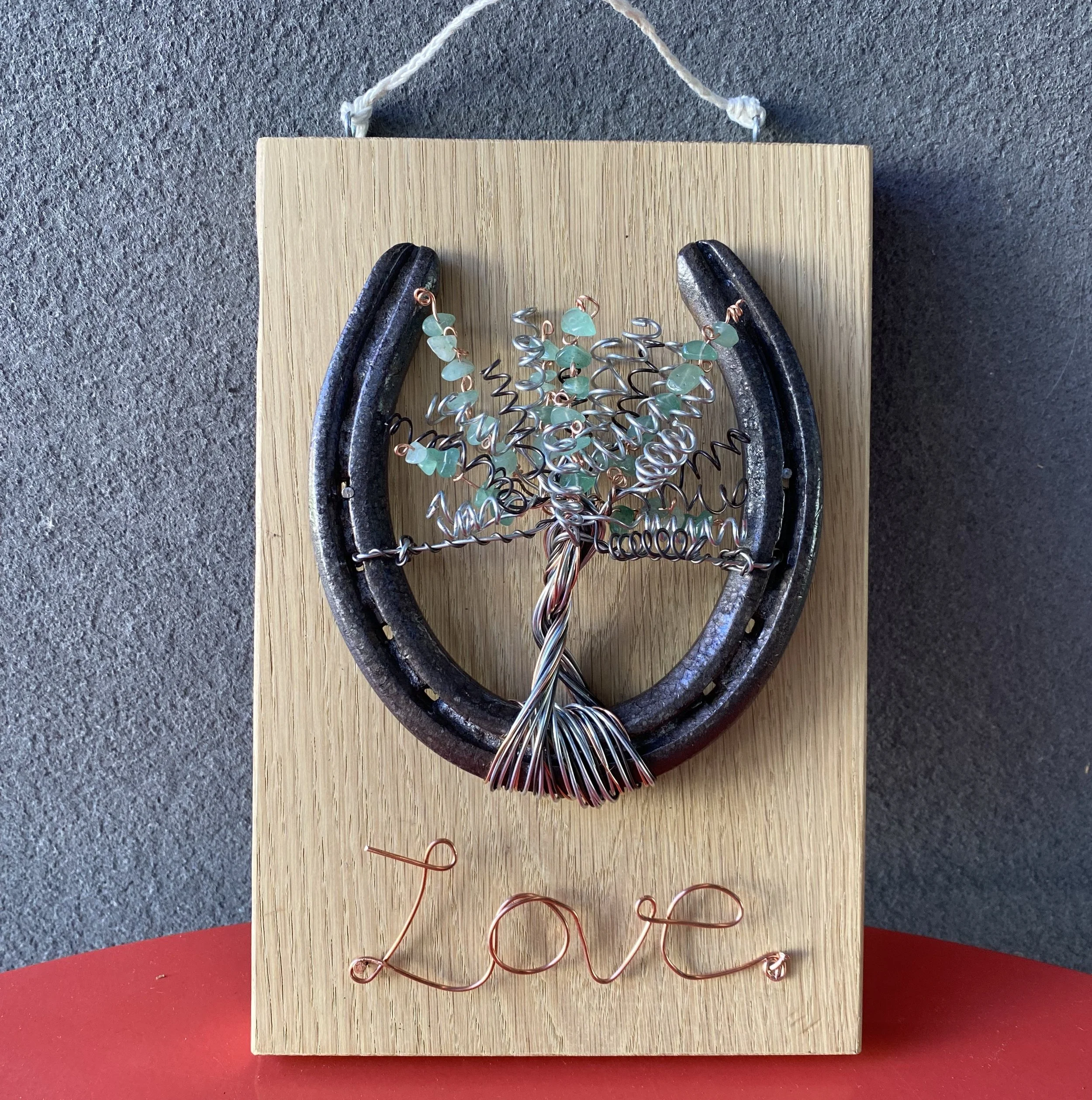 Horseshoe on wooden board with wire tree and word "Love" made out of wire