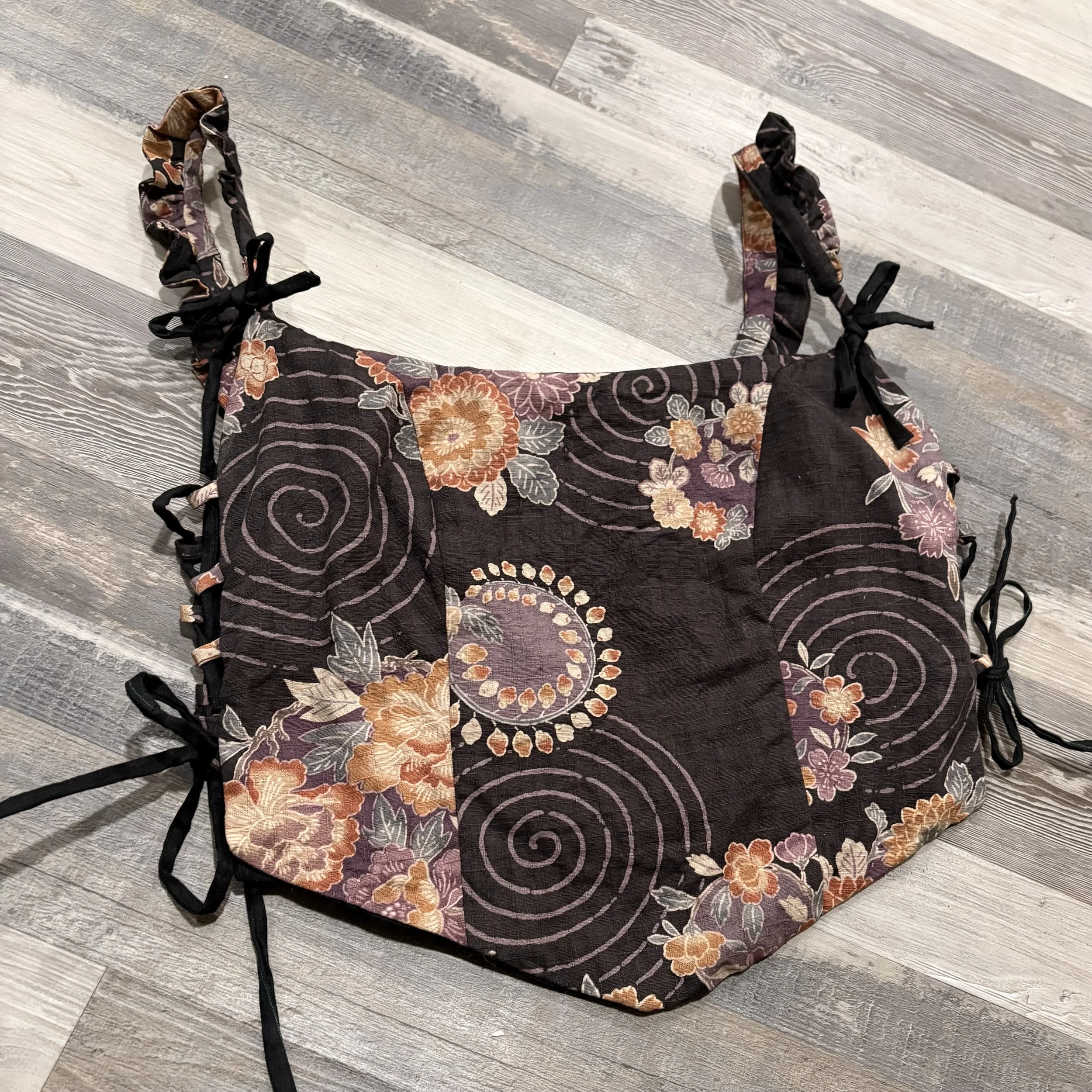 Handmade corset or waistcoat made out of dark brown fabric with spirals and florals