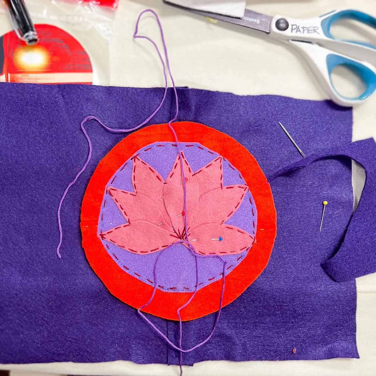 Pink lotus design with red circle on purple background