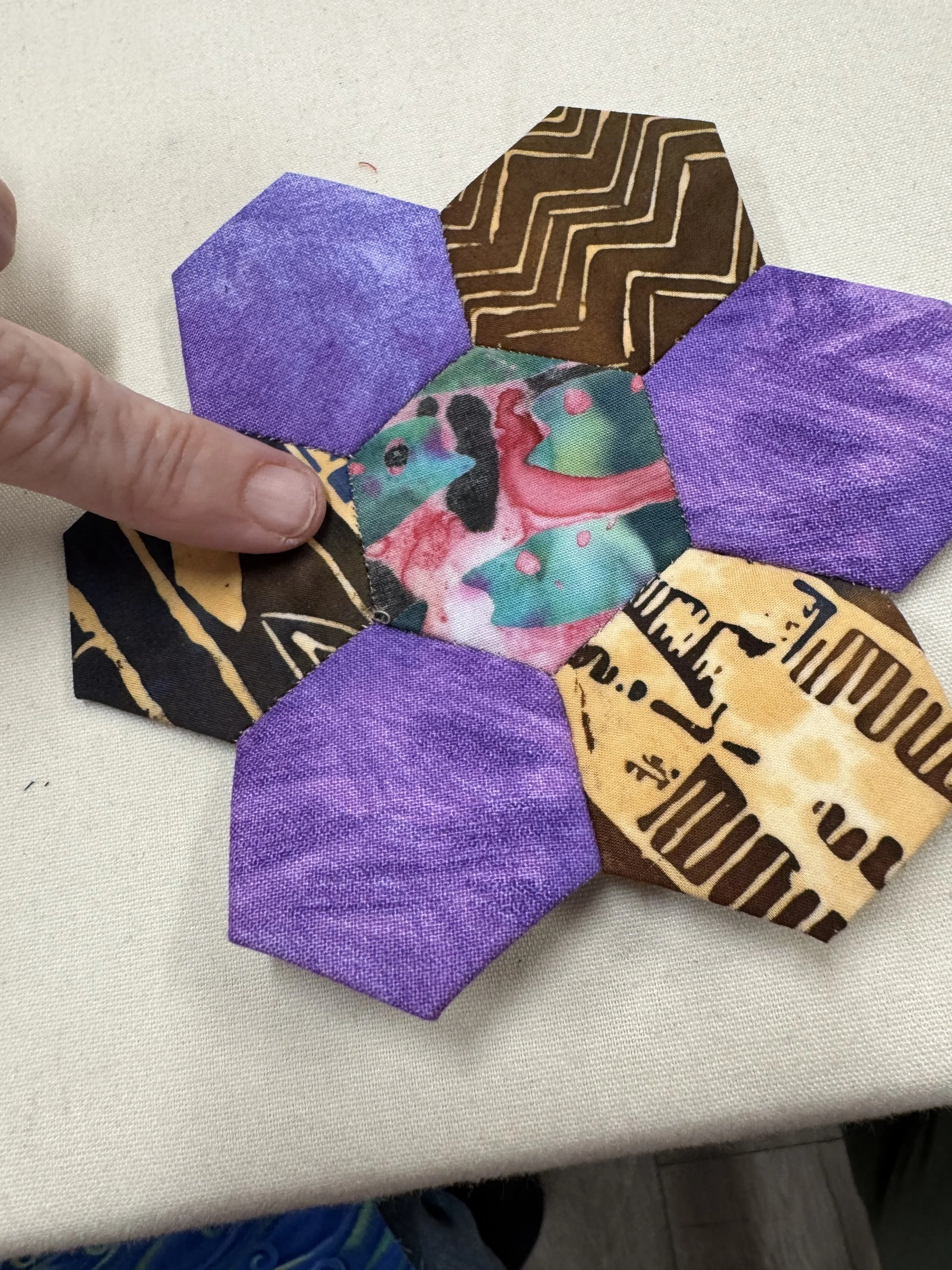 Hexagon-shaped pieces of purple and brown fabric sewn to form flower shape