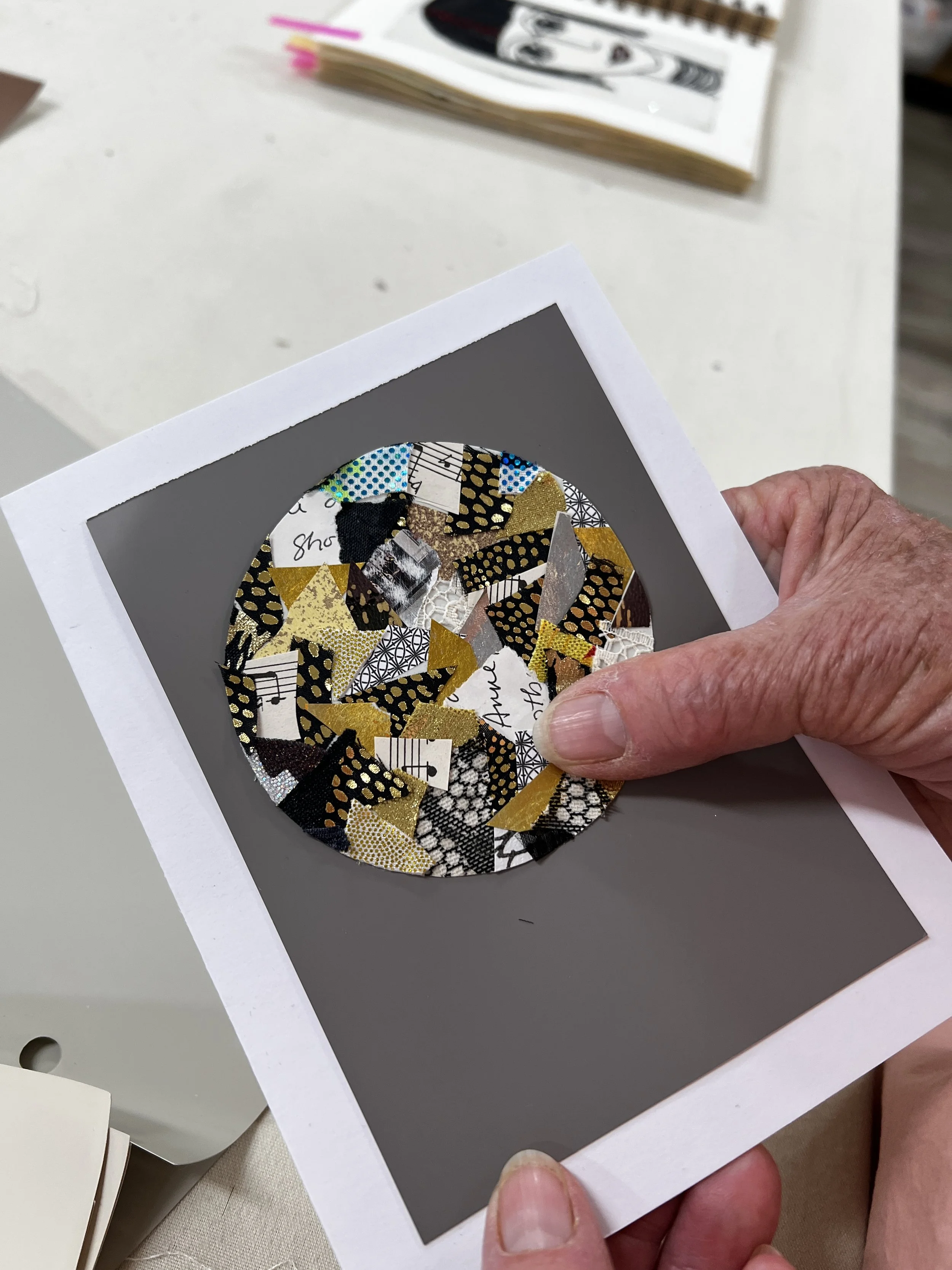 Paper collage in shape of a circle on grey background placed on white card
