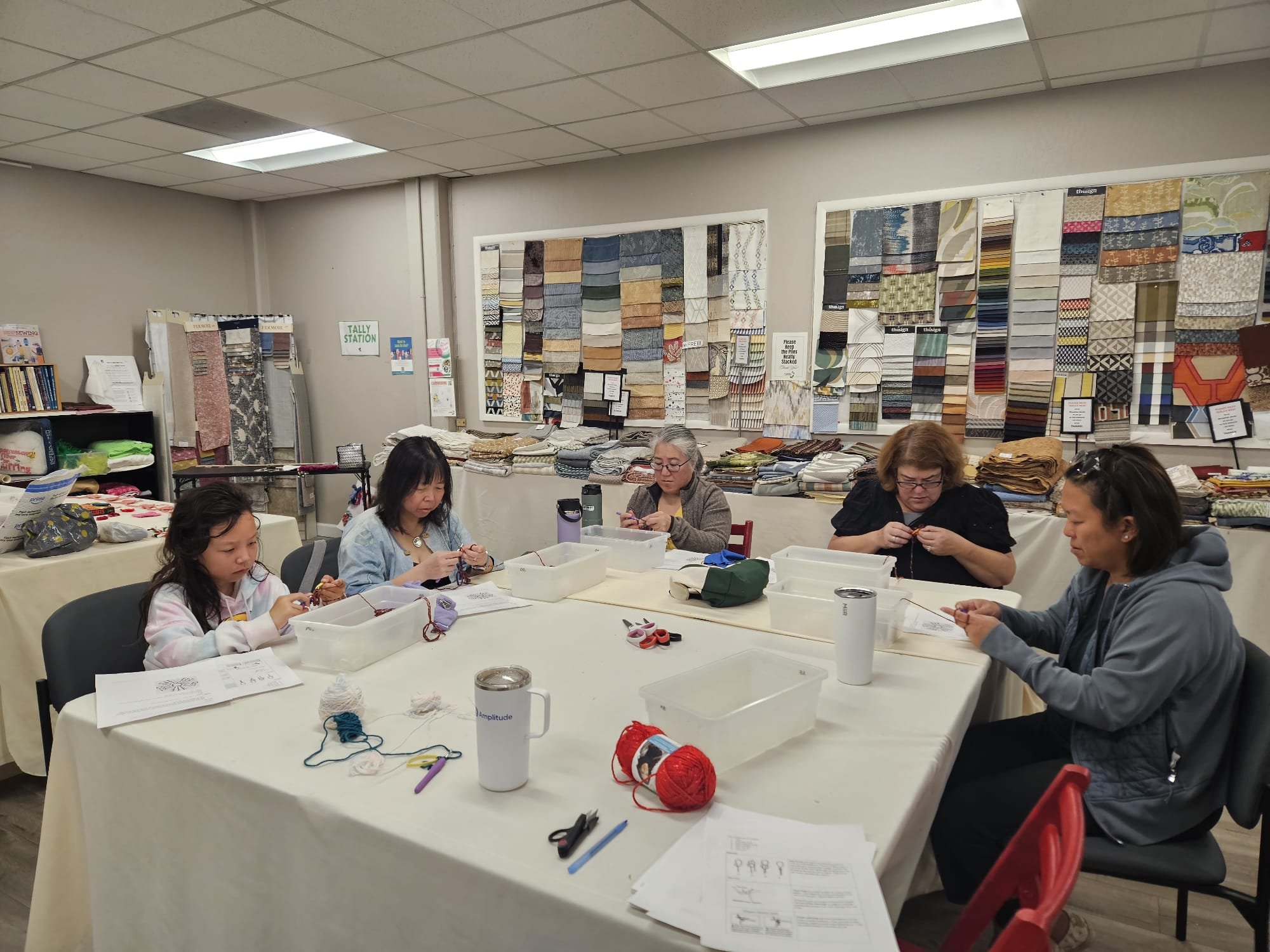 Five women seated around a table crocheting yarn