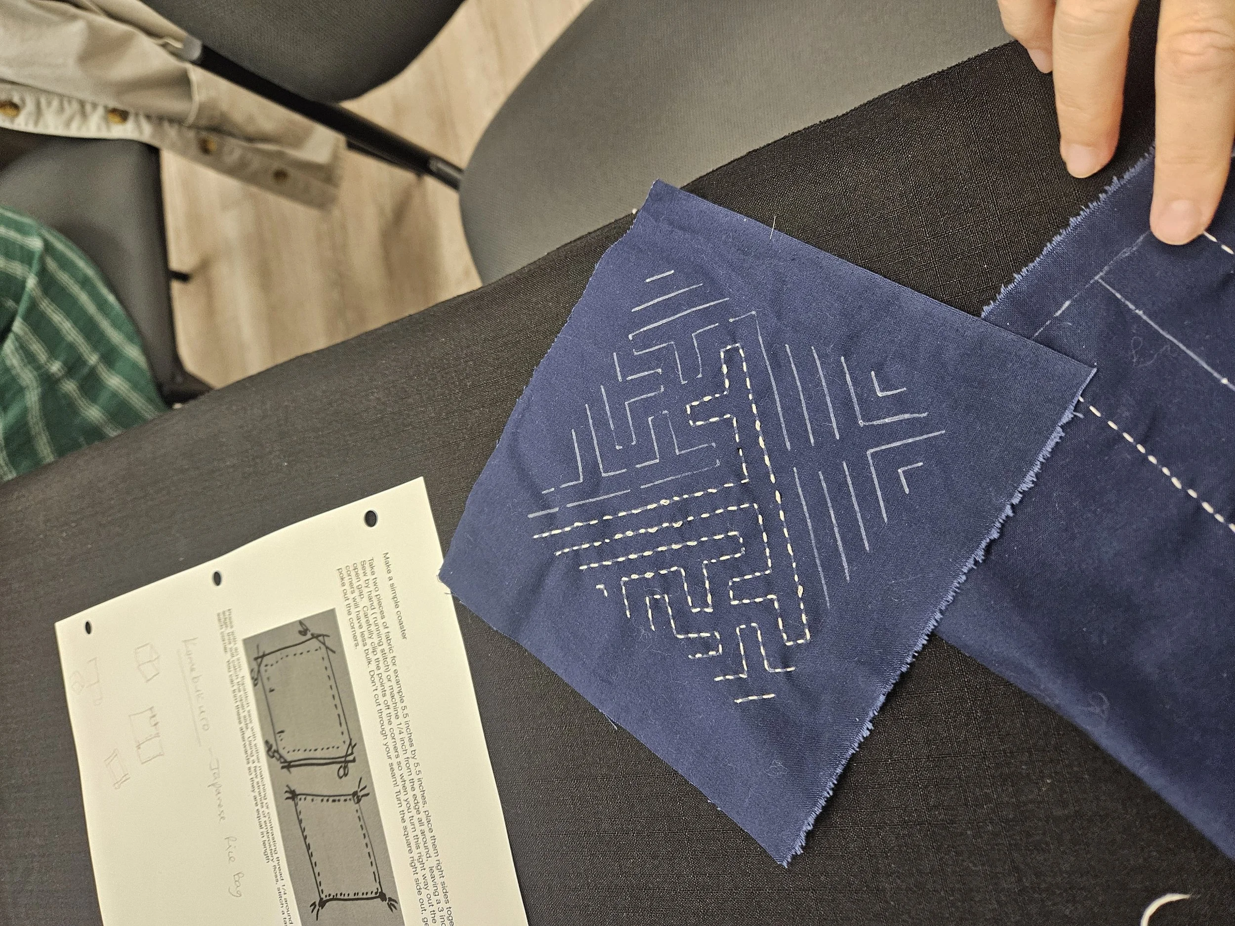 White stitched geometric design on dark blue fabric square