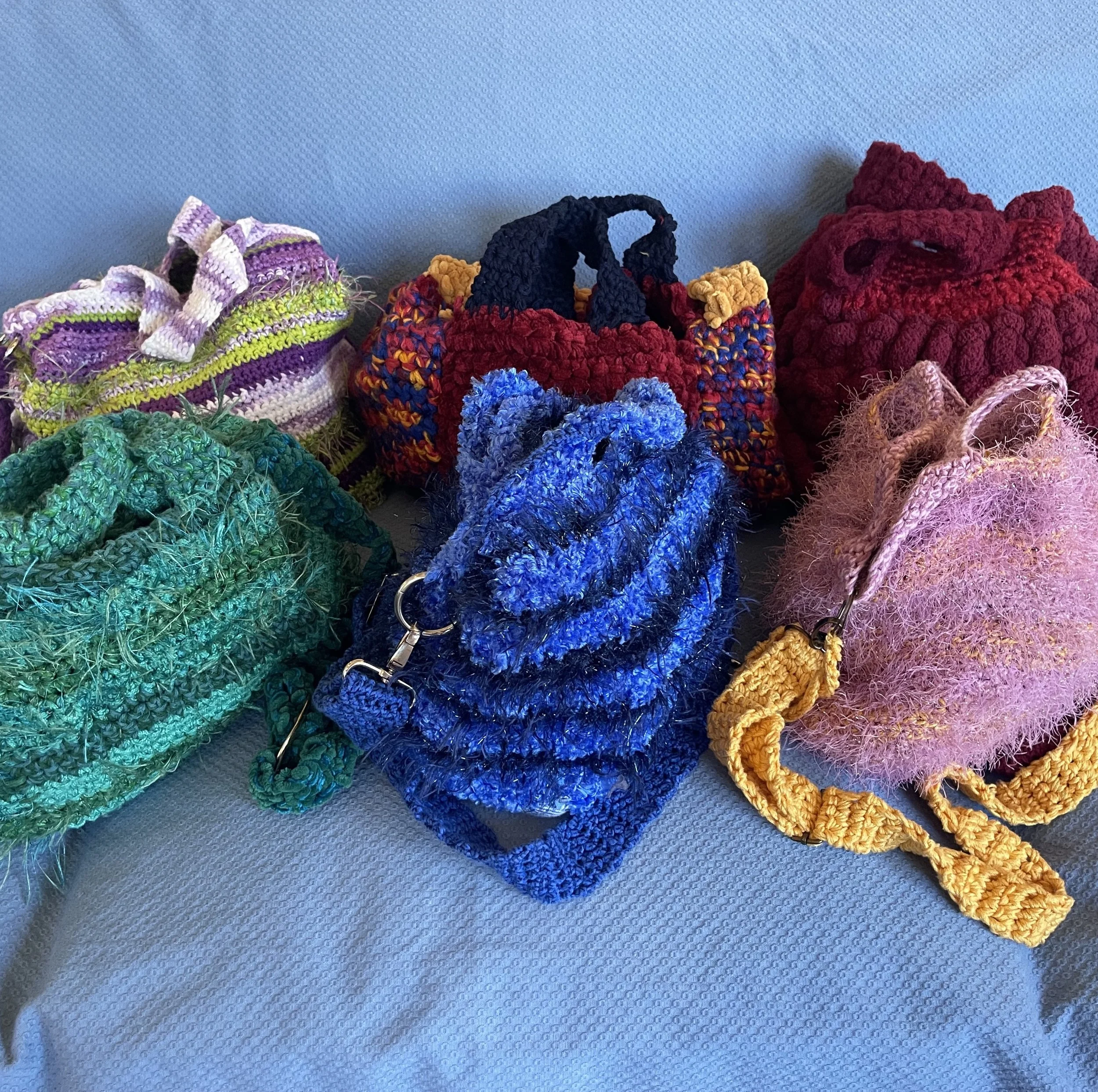 Six crocheted bags with straps in different colors