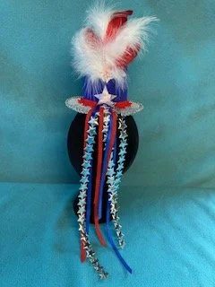 Back view of hat with trailing red, white & blue ribbons and trims
