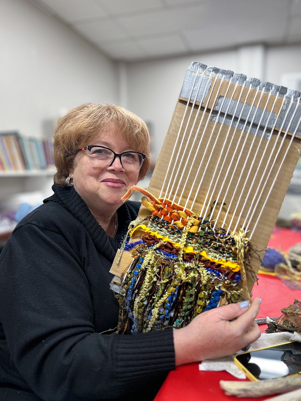 Woman holding up cardboard loom with weaving