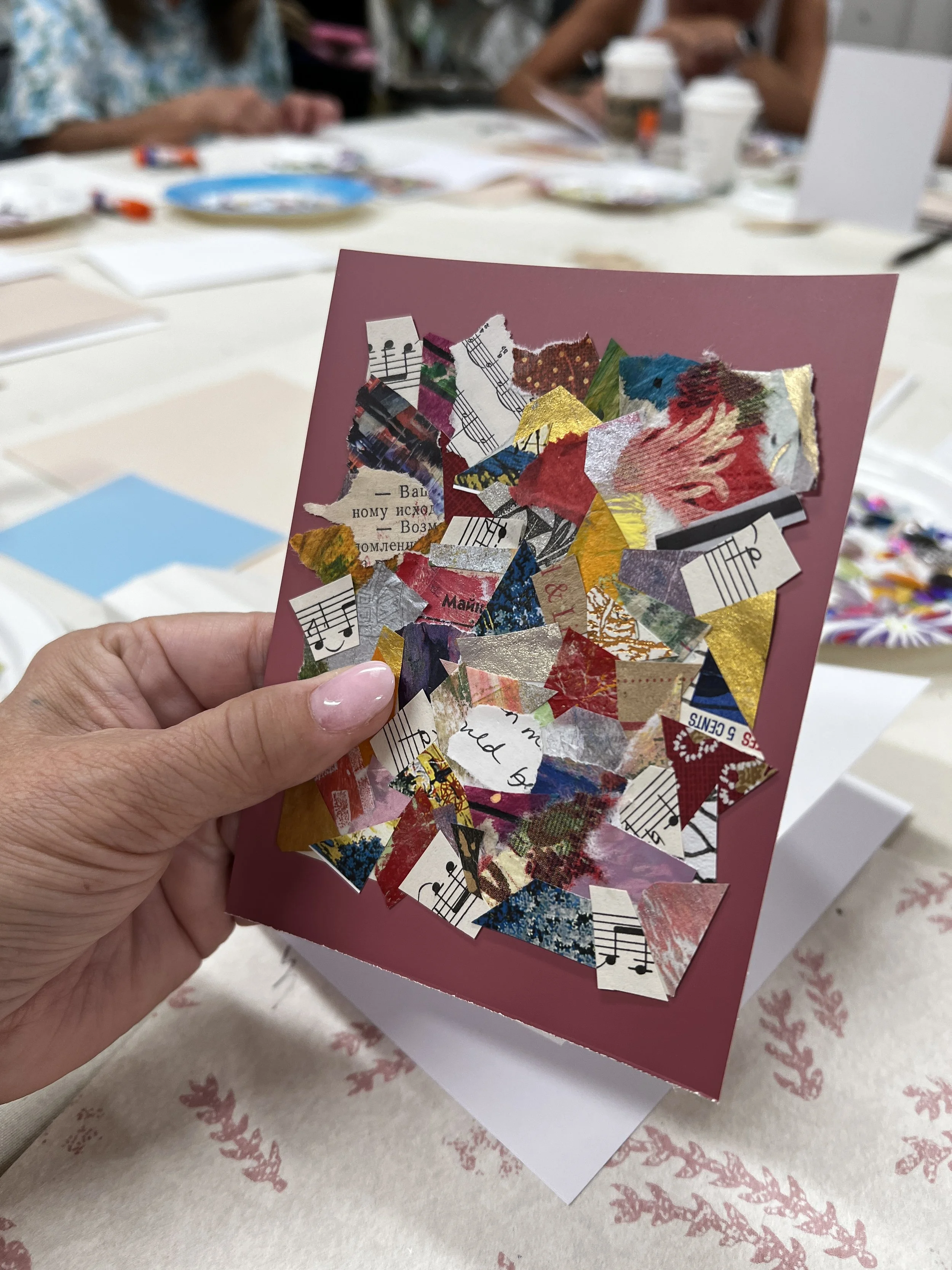 Hand holding up paper collage greeting card with reddish background