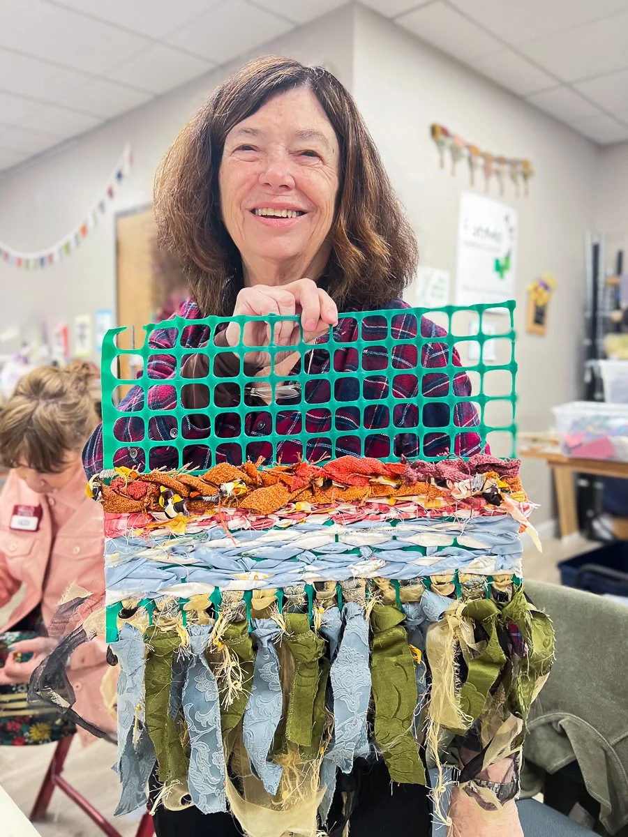 Standing woman holding weaving project