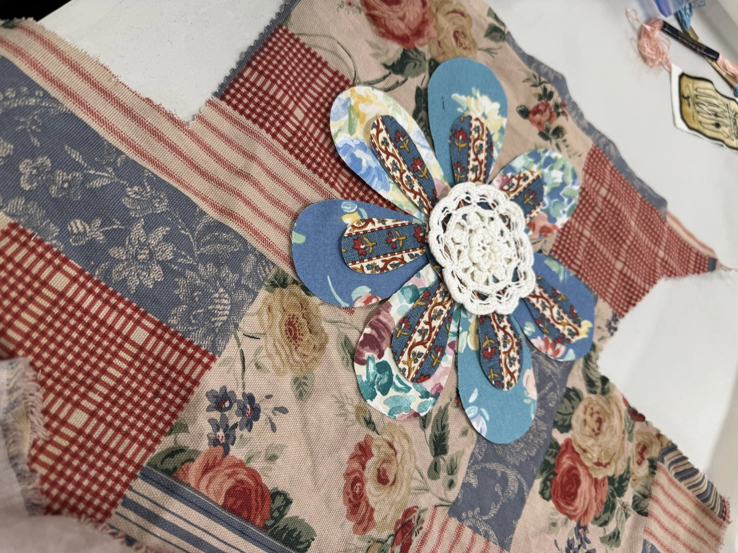 Blue fabric flower applique on patchwork fabric