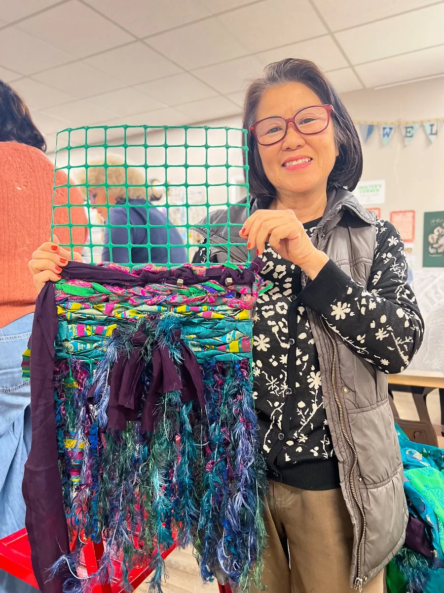 Standing woman holding weaving project