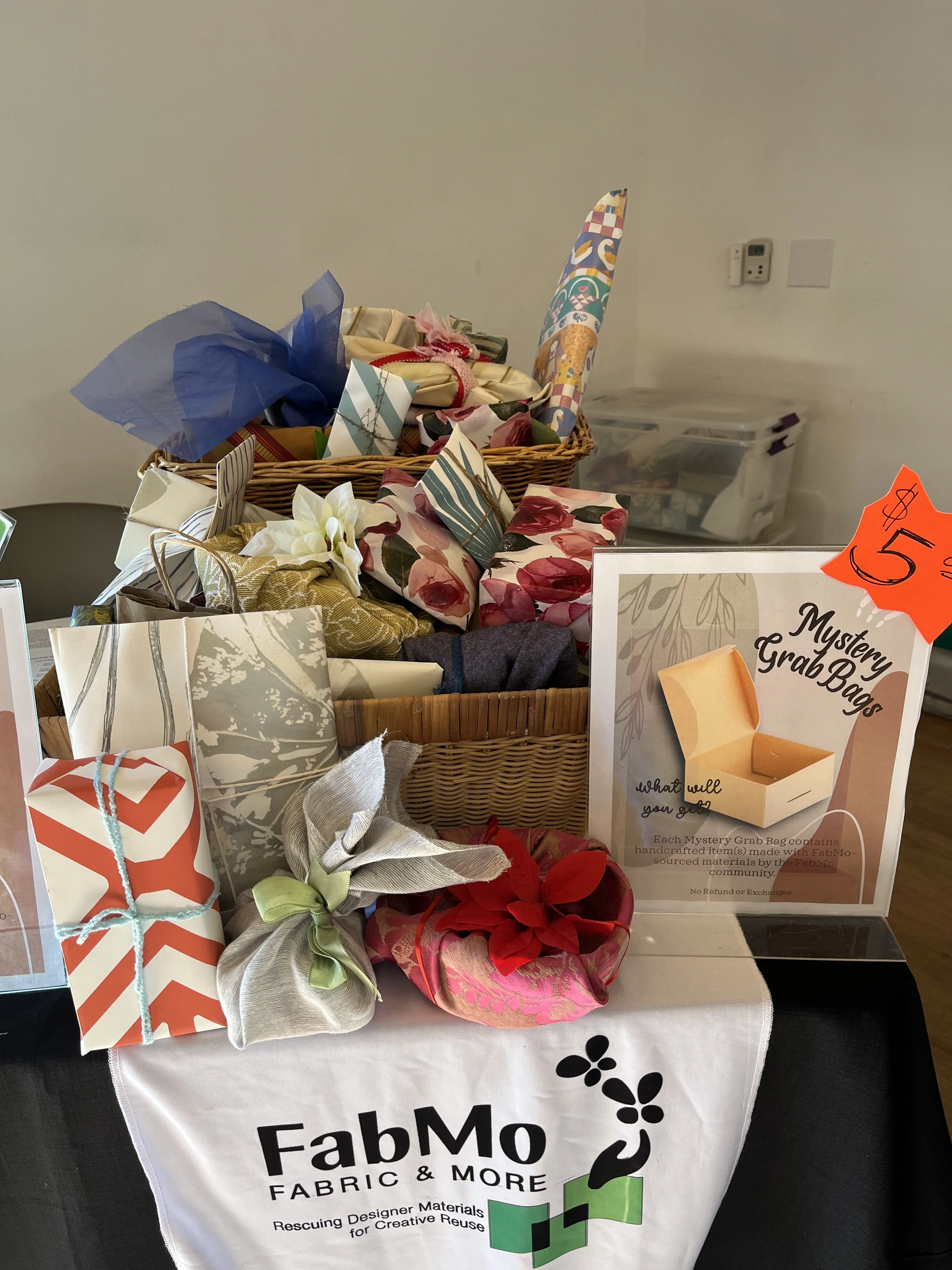 Assortment of gift wrapped packages in basket or on small table with FabMo sign