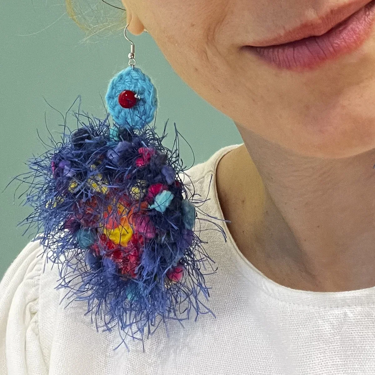 Close up of person wearing blue crocheted earring
