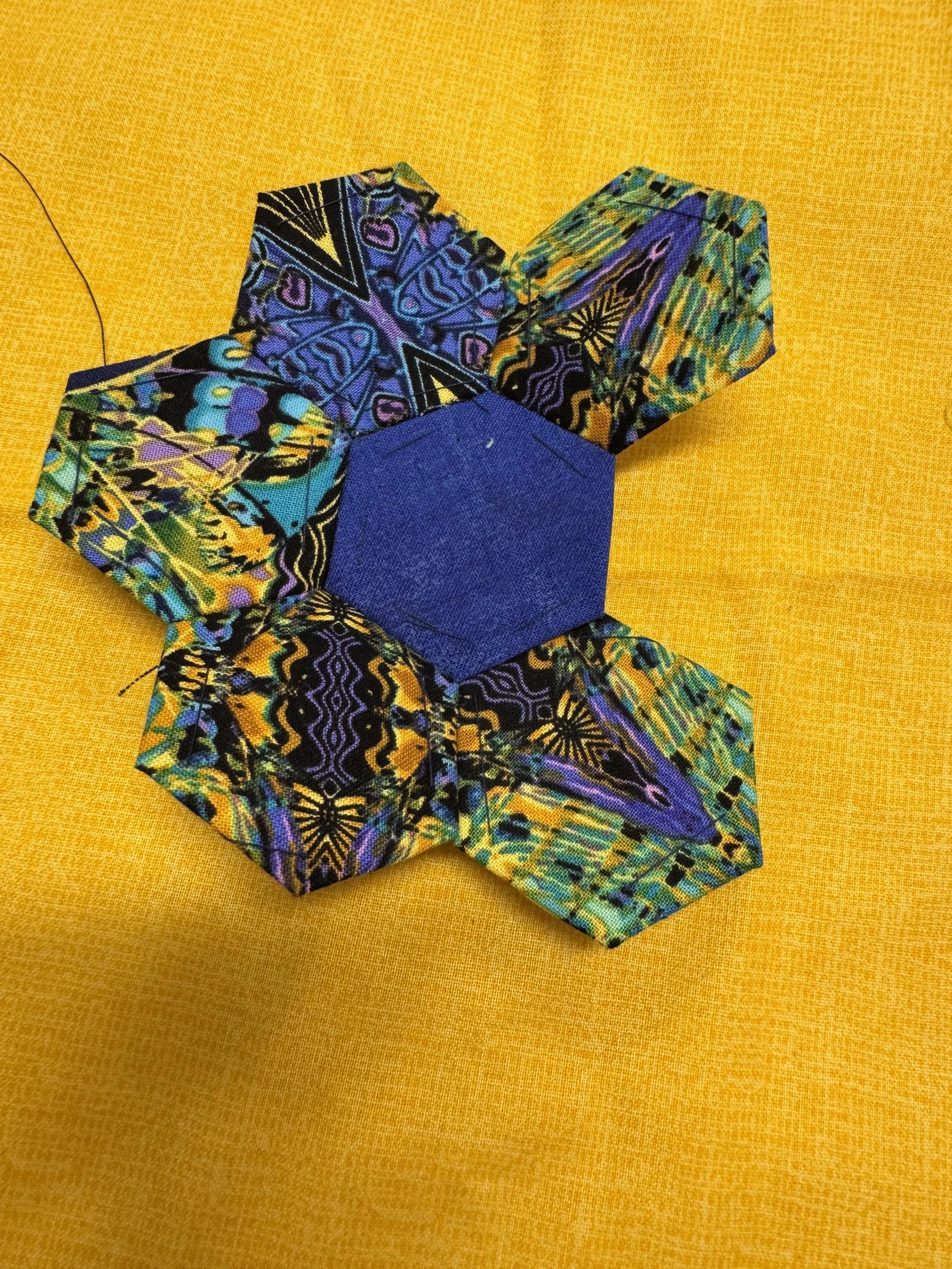 Hexagon-shaped pieces of multicolored fabric sewn to form flower shape