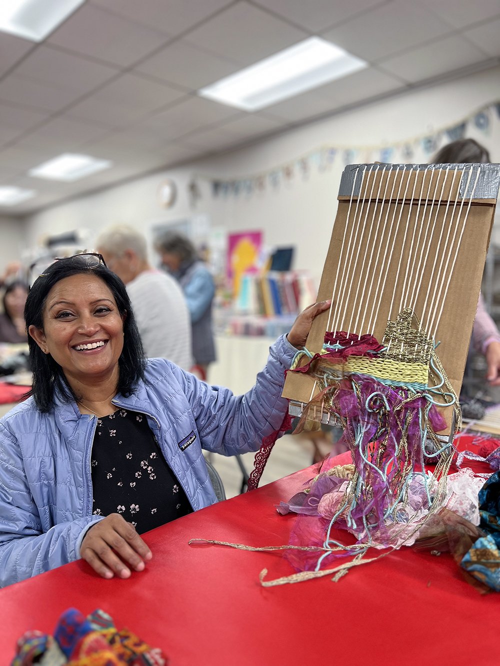 Woman holding up cardboard loom with weaving