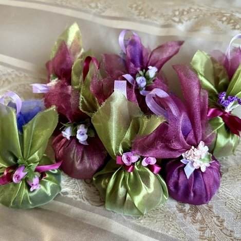 Lavender sachets wrapped in purple and green silky fabric tied with small artificial flowers