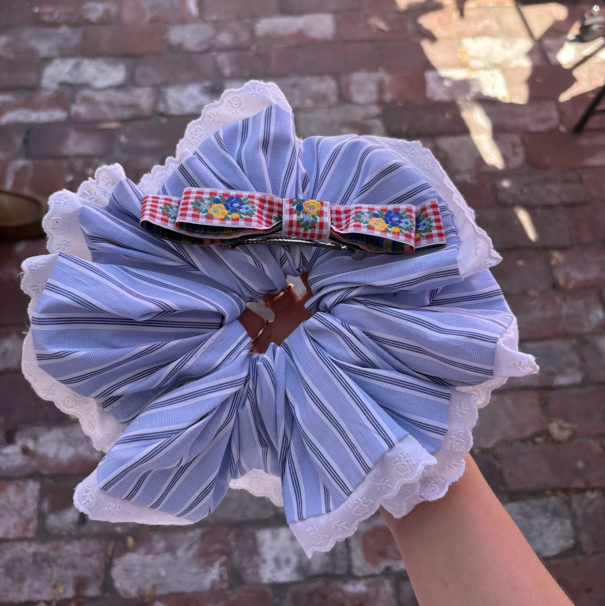 Person holding large blue scrunchie and hair clip
