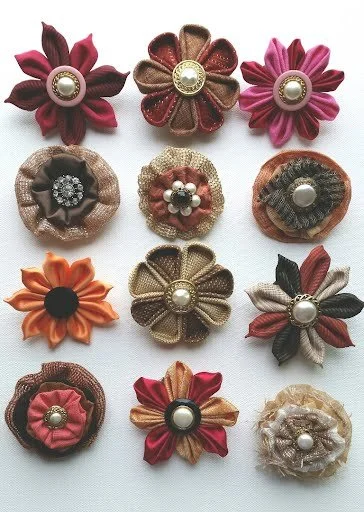 A dozen fabric flowers with button centers in beige, pinks, oranges, and browns