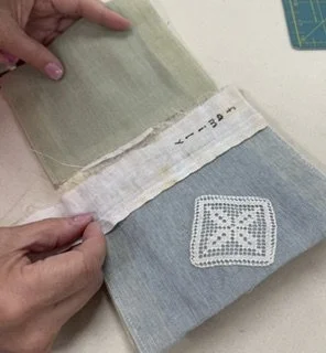 Hands holding open fabric book with pale blue page with small lace doily