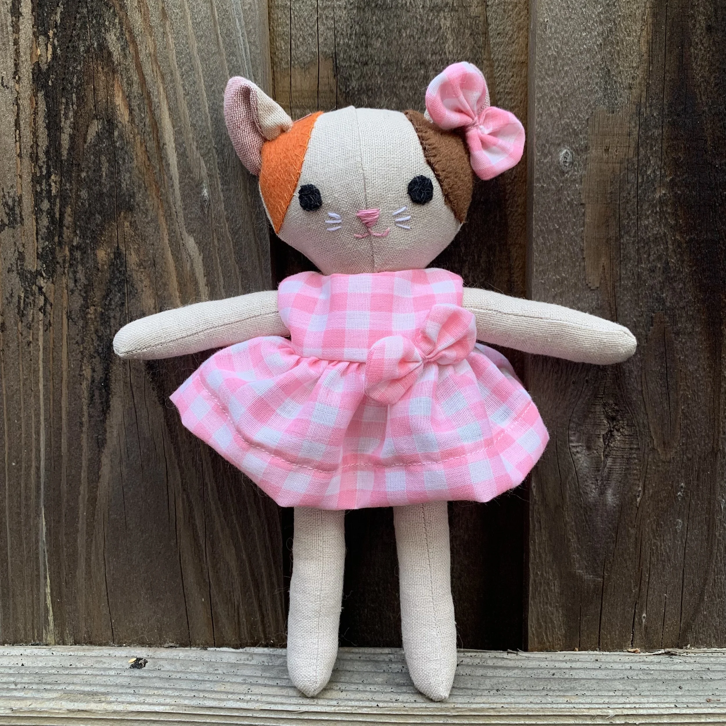 Stuffed kitten doll wearing pink & white check dress