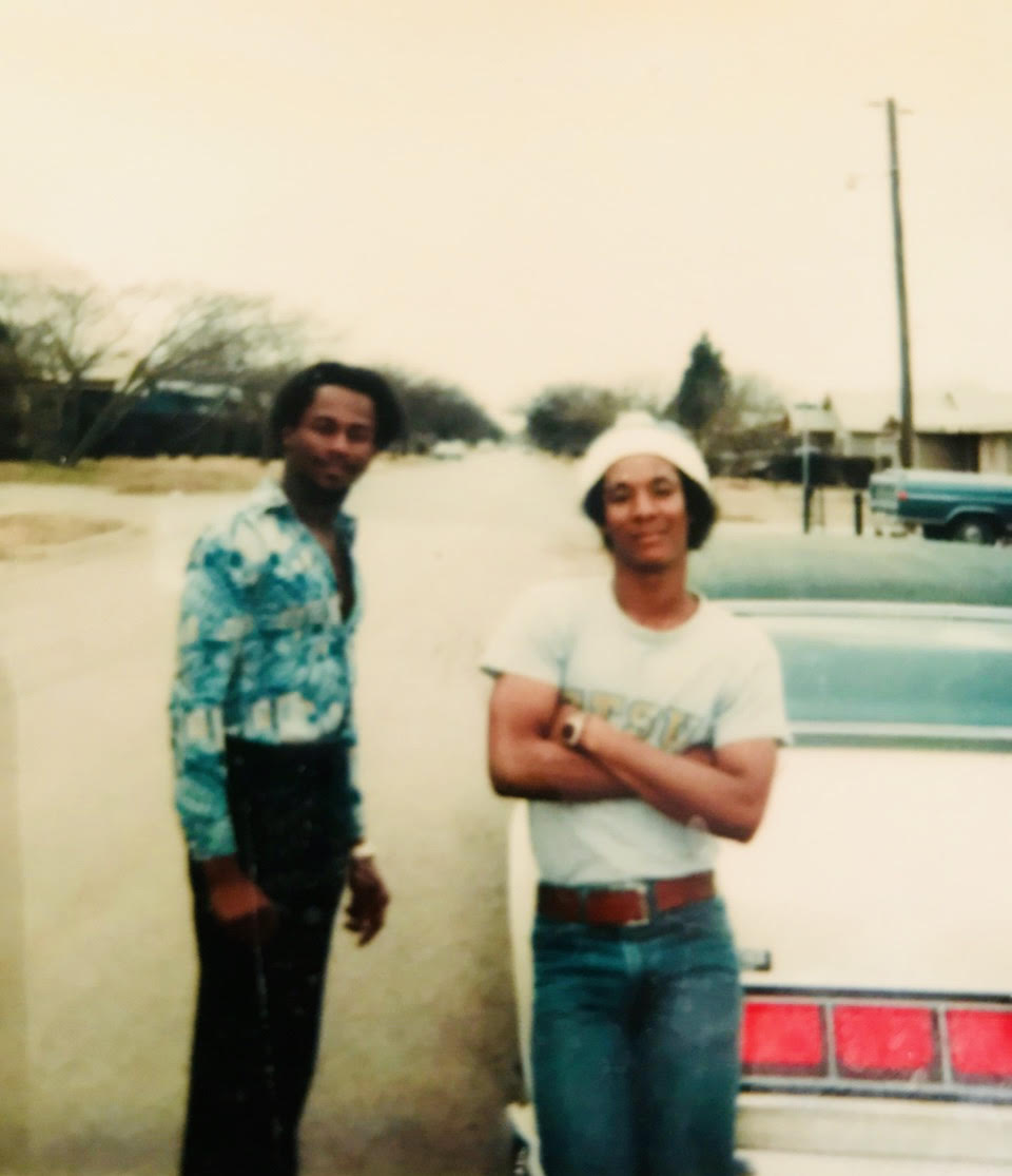 Carl as a young man (leaning on the car).