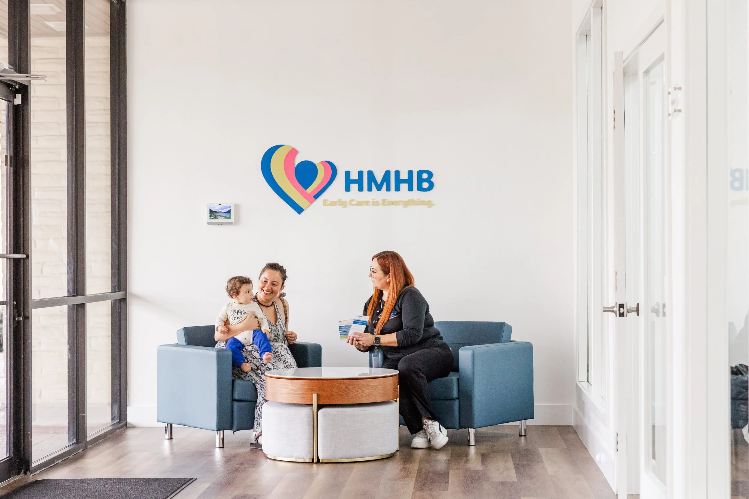 New mother holding her baby while receiving postpartum support resources and maternal health guidance from a professional.