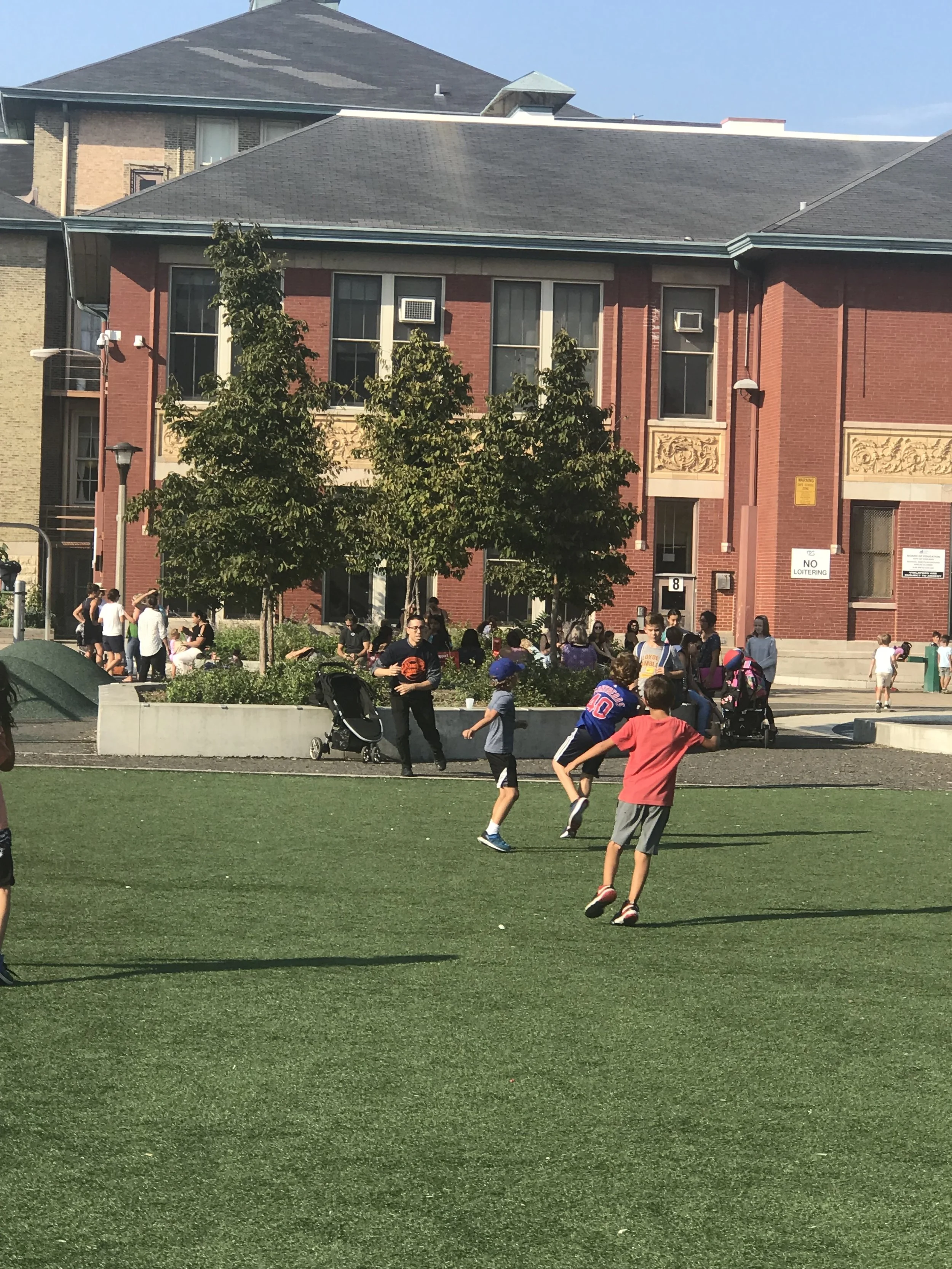 Families, administrators and students playing on our environmentally friendly playground during summer orientation.