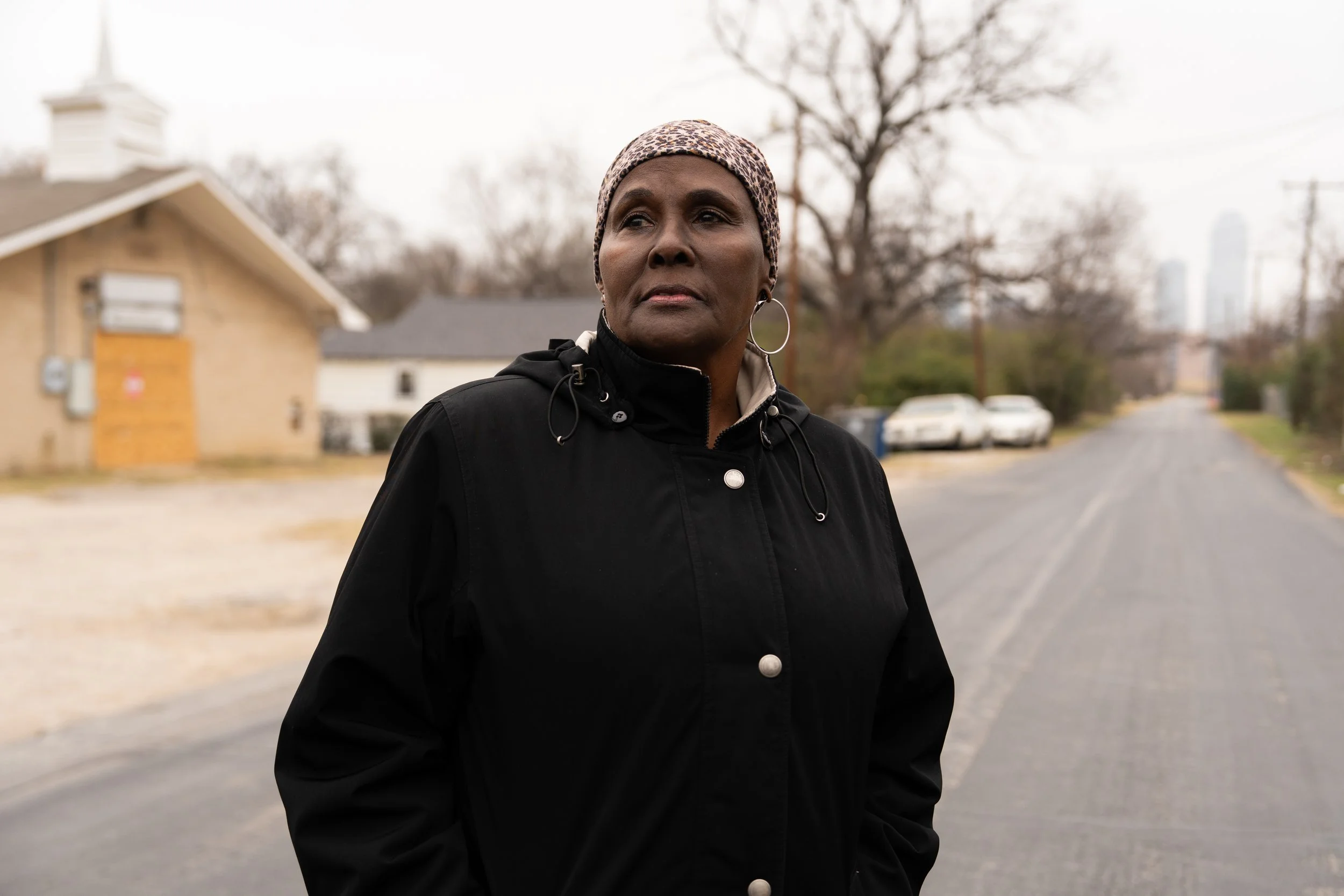 Paula Hutchison stands on a street in the West Main neighborhood where she grew up in Dallas. What was once a vibrant community she remembers now has only two homes remaining. One of them is her childhood home, where her sister now lives. The neighbo